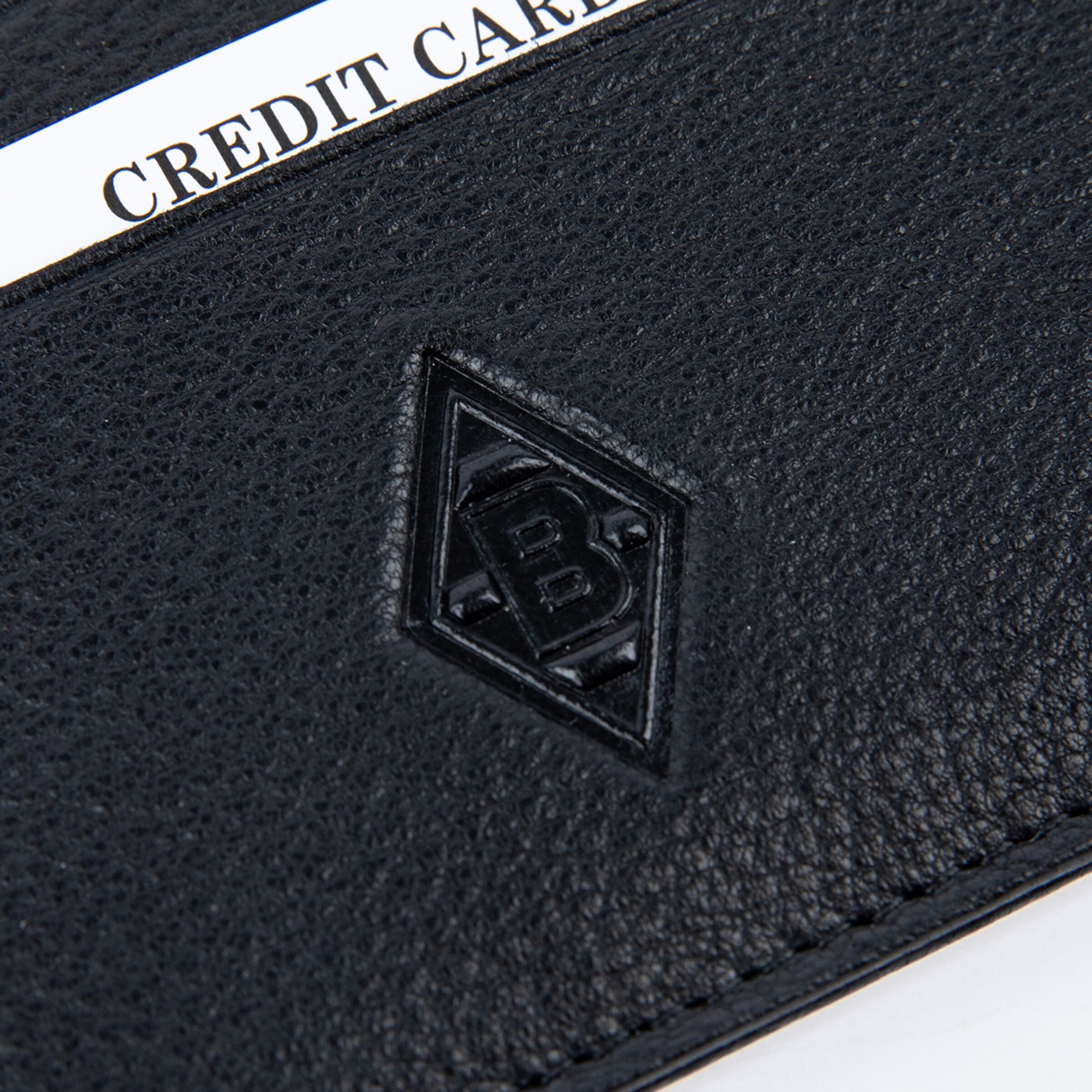 Nahaufnahme eines schwarzen Lederportemonnaies mit geprägtem „B“-Rautenlogo und einer weißen Karte mit der Aufschrift „CREDIT CA“.