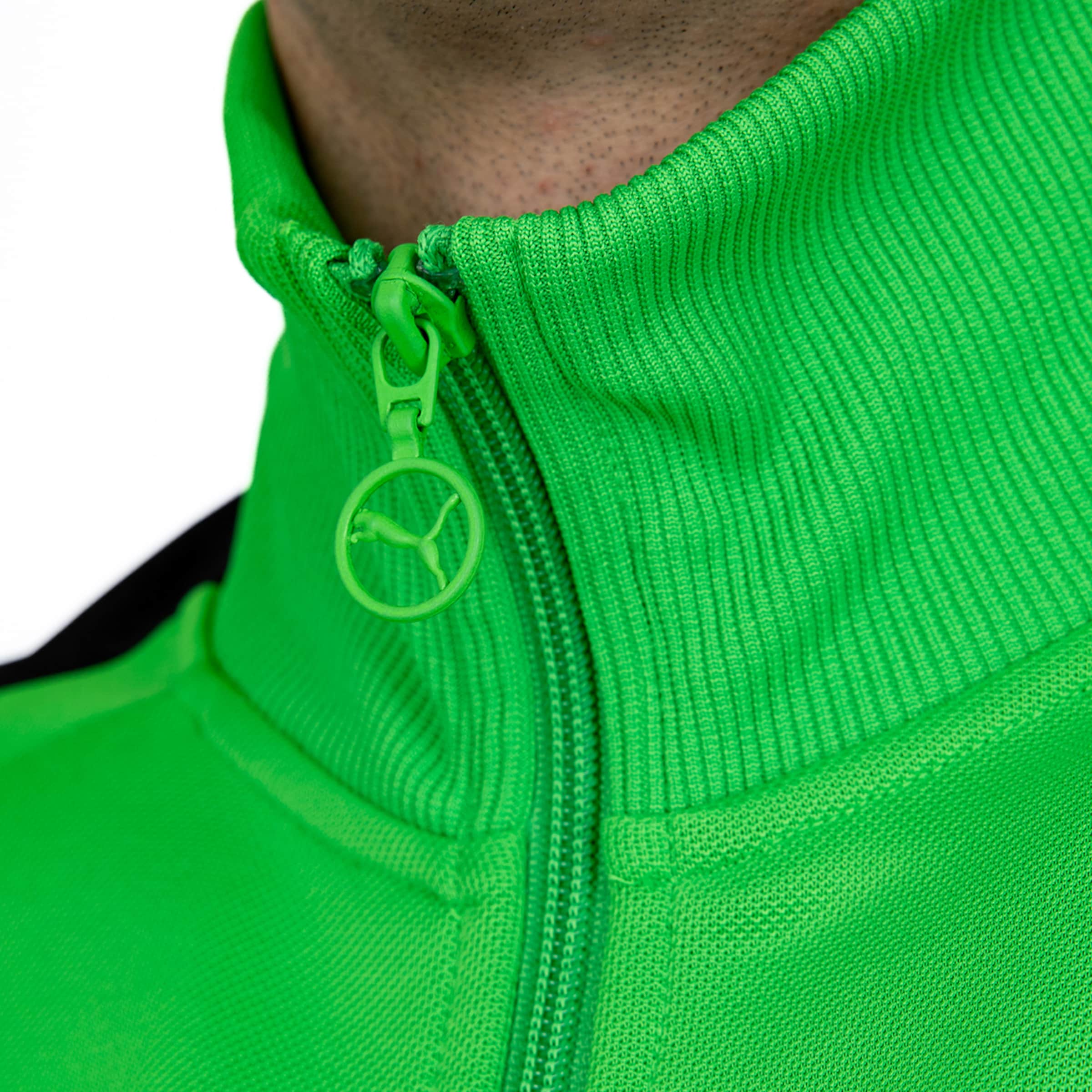 Nahaufnahme einer neongrünen Puma-Trainingsjacke mit geripptem Kragen und rundem Reißverschluss-Zipper mit Markenlogo.