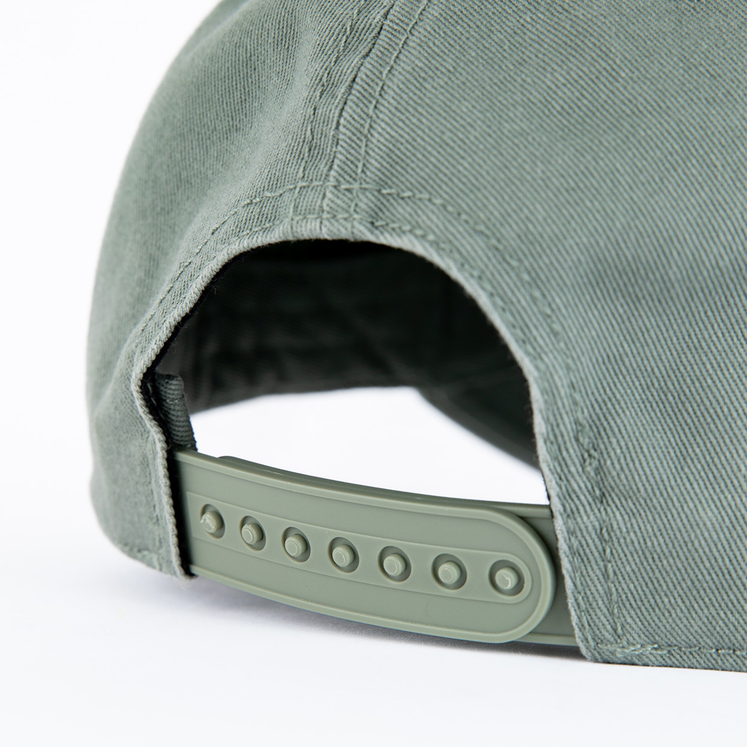 Adjustable closure mechanism of a green baseball cap.