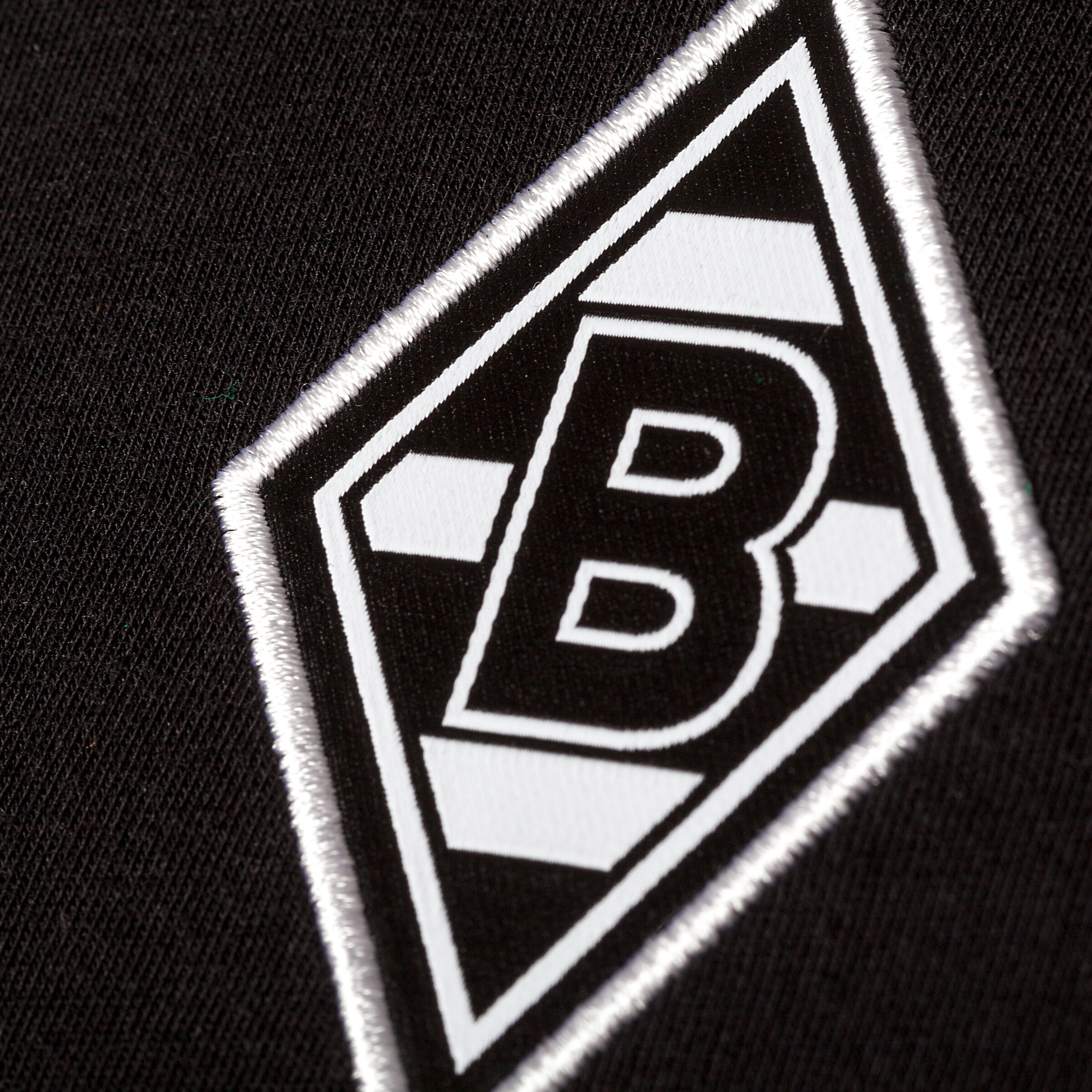 Emblem von Borussia Mönchengladbach auf schwarzem Stoff mit grafischen Elementen.