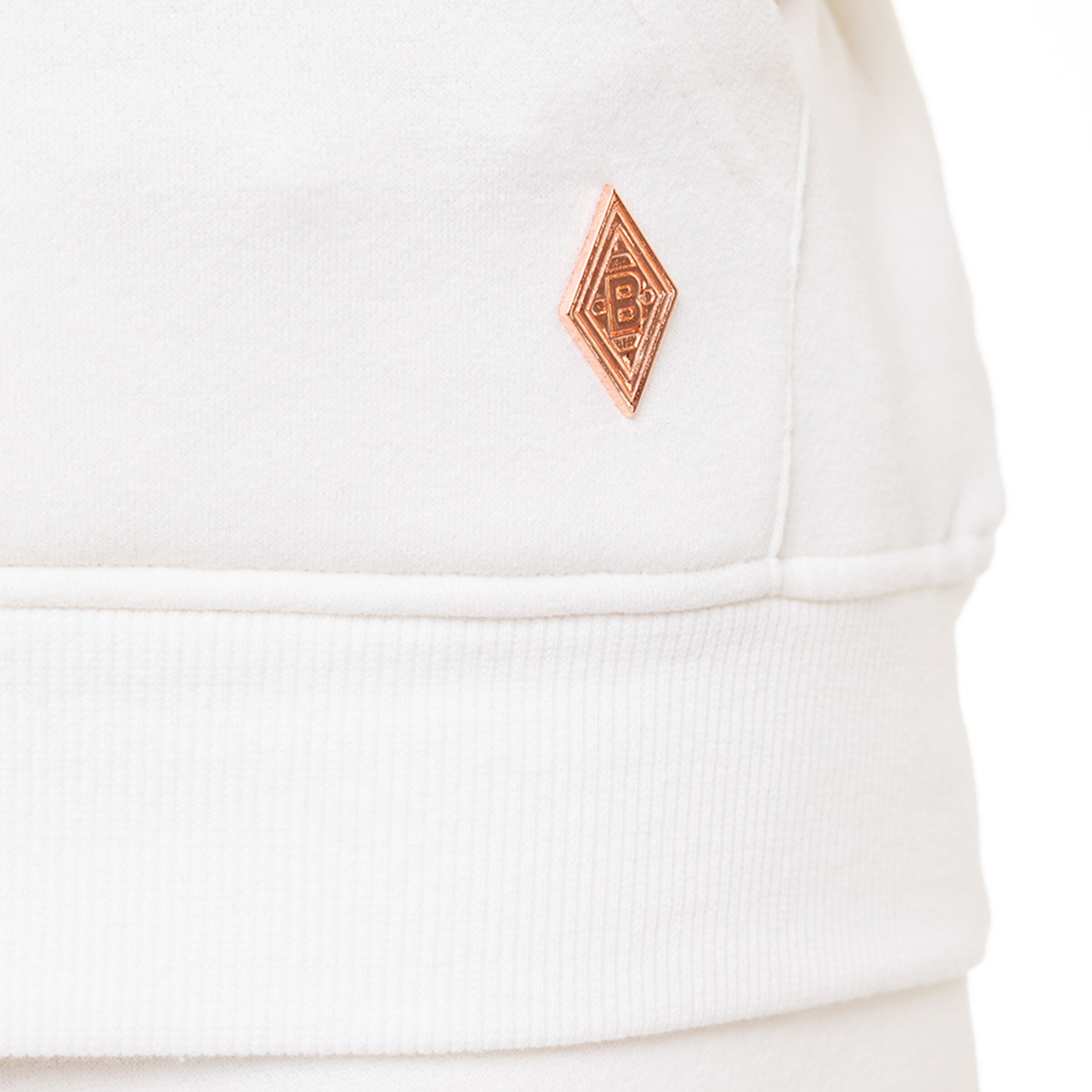 Detailaufnahme eines weißen Sweatshirts mit einem bronzefarbenen Logo-Patch von Borussia Mönchengladbach.