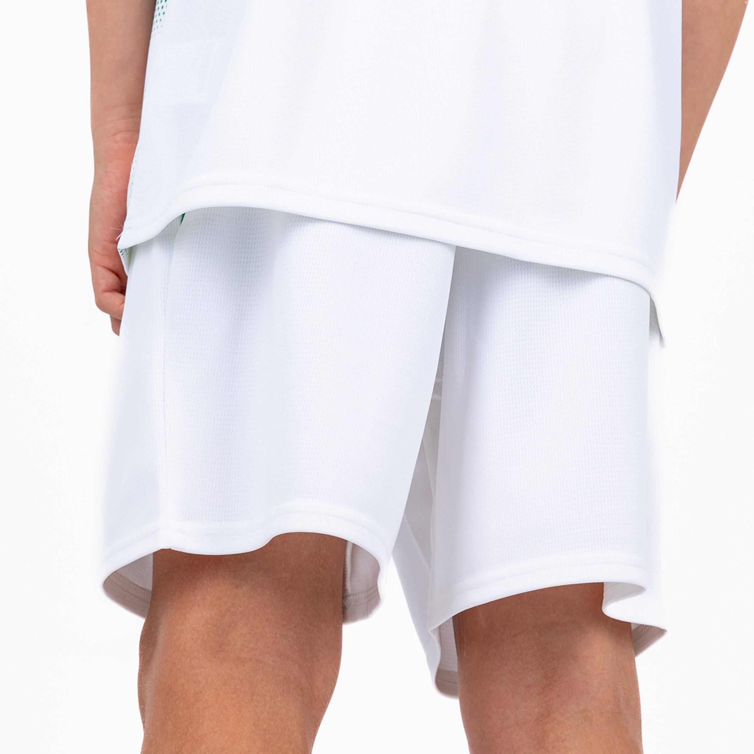 Rückansicht einer Person in weißem Sporttrikot und weißen Mesh-Shorts vor einem neutralen weißen Hintergrund.