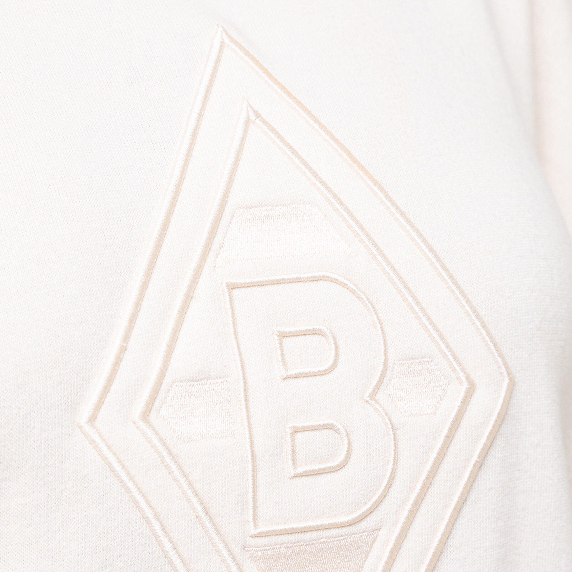 Detailansicht eines weißen Sweatshirts mit gesticktem Borussia Mönchengladbach Logo.