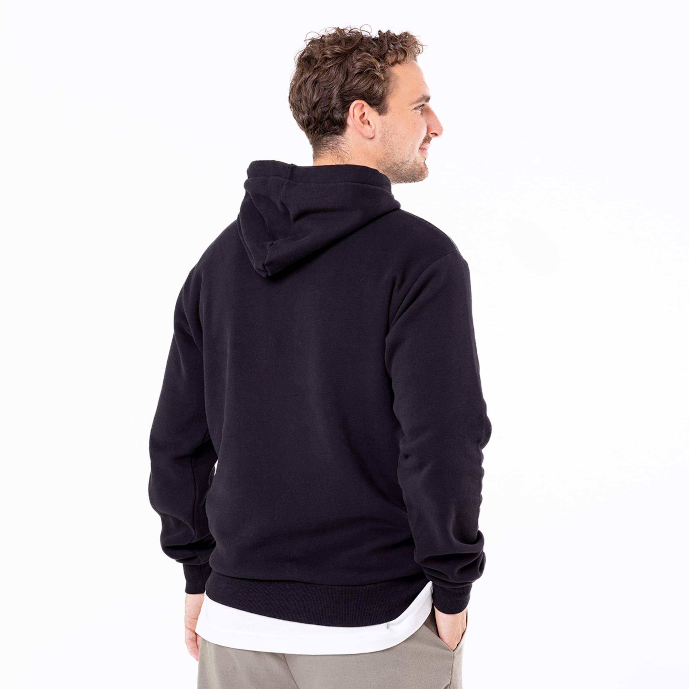Mann mit schwarzem Hoodie von hinten fotografiert mit kurzen lockigen Haaren und neutralem Ausdruck.
