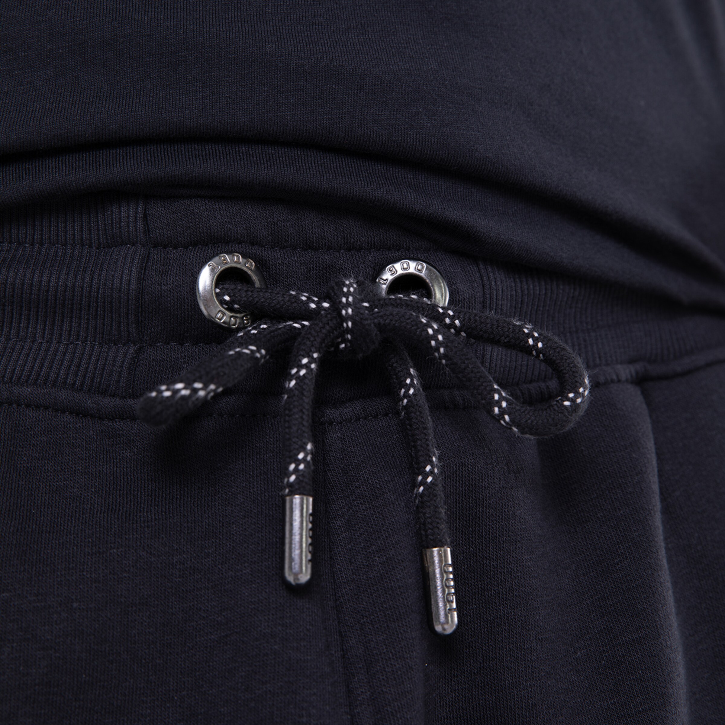 Detailaufnahme eines schwarzen Sweatpants mit Kordelzug und Metallösen.