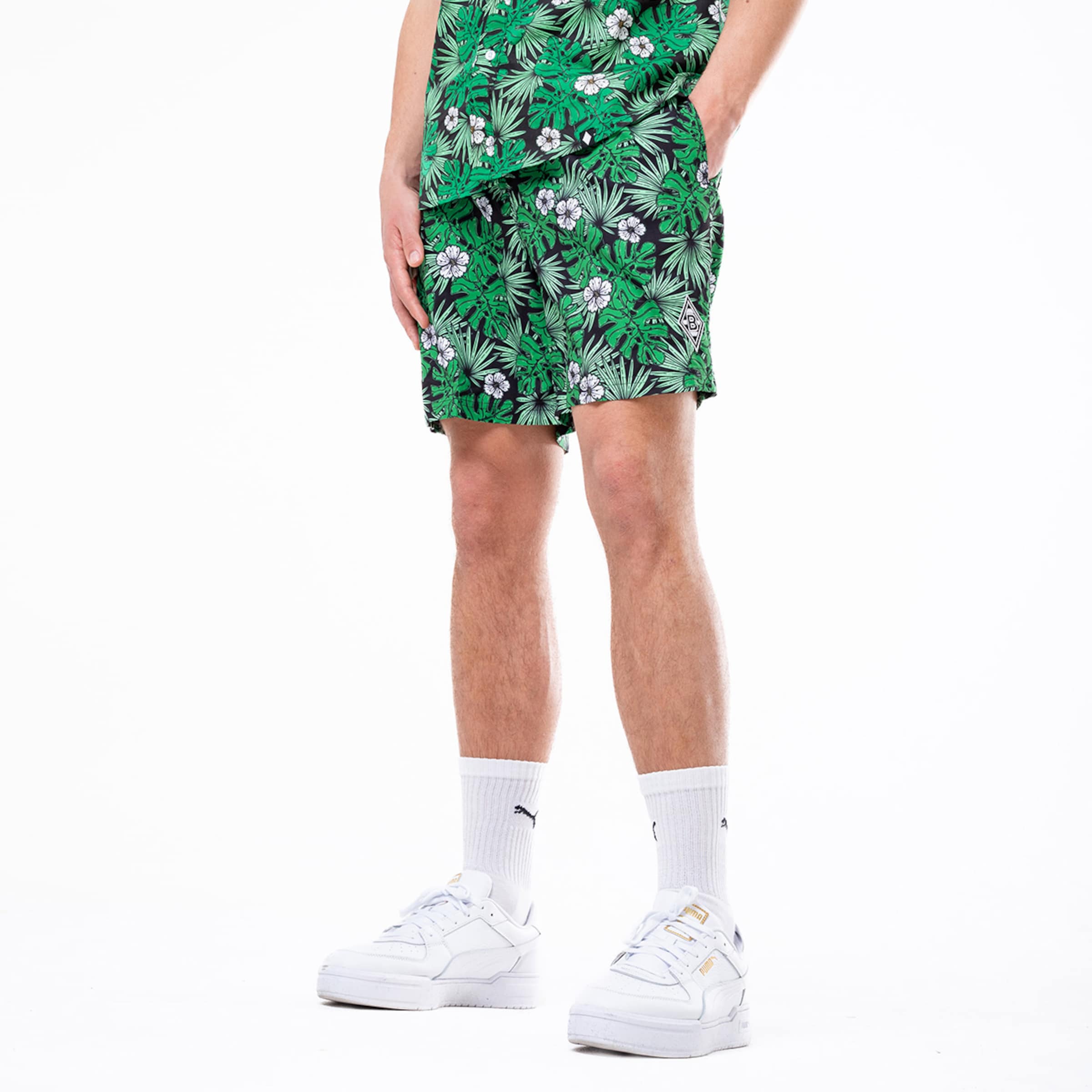 Ein Mann mit kurzen grünen Hosen und passendem Hemd mit blühenden Pflanzenmustern.