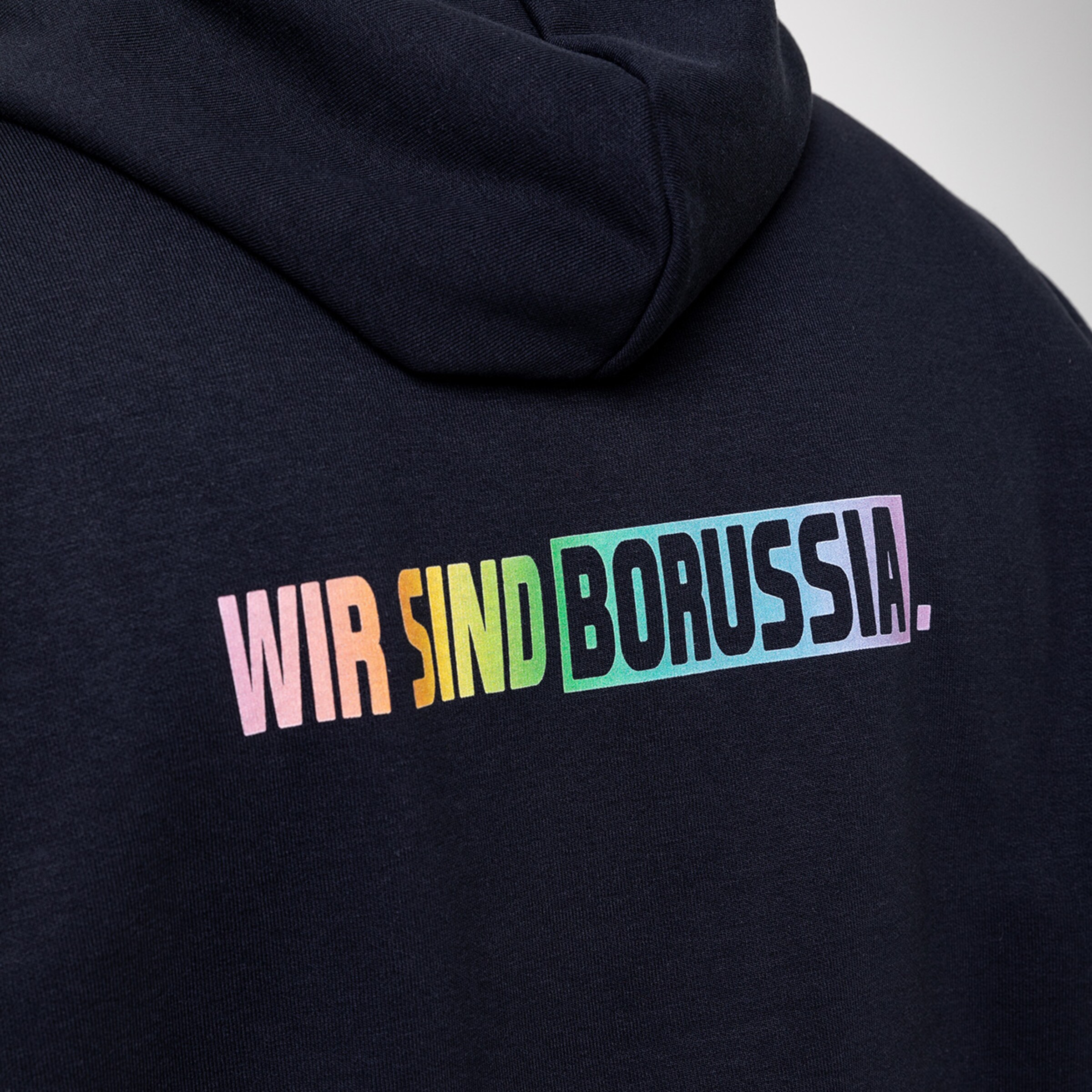 Schwarzer Kapuzenpullover mit dem Schriftzug WIR SIND BORUSSIA. auf dem Rücken.