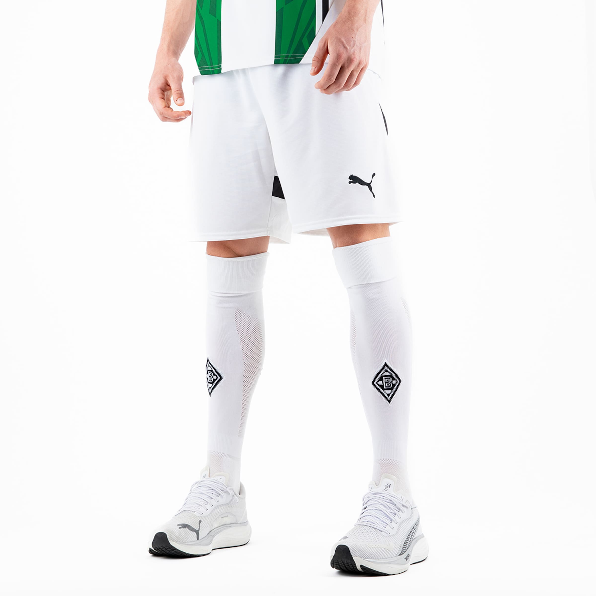 Ein Spieler trägt das aktuelle Borussia Mönchengladbach Trikot weiße Shorts und Socken mit dem Puma-Logo und Vereinswappen.