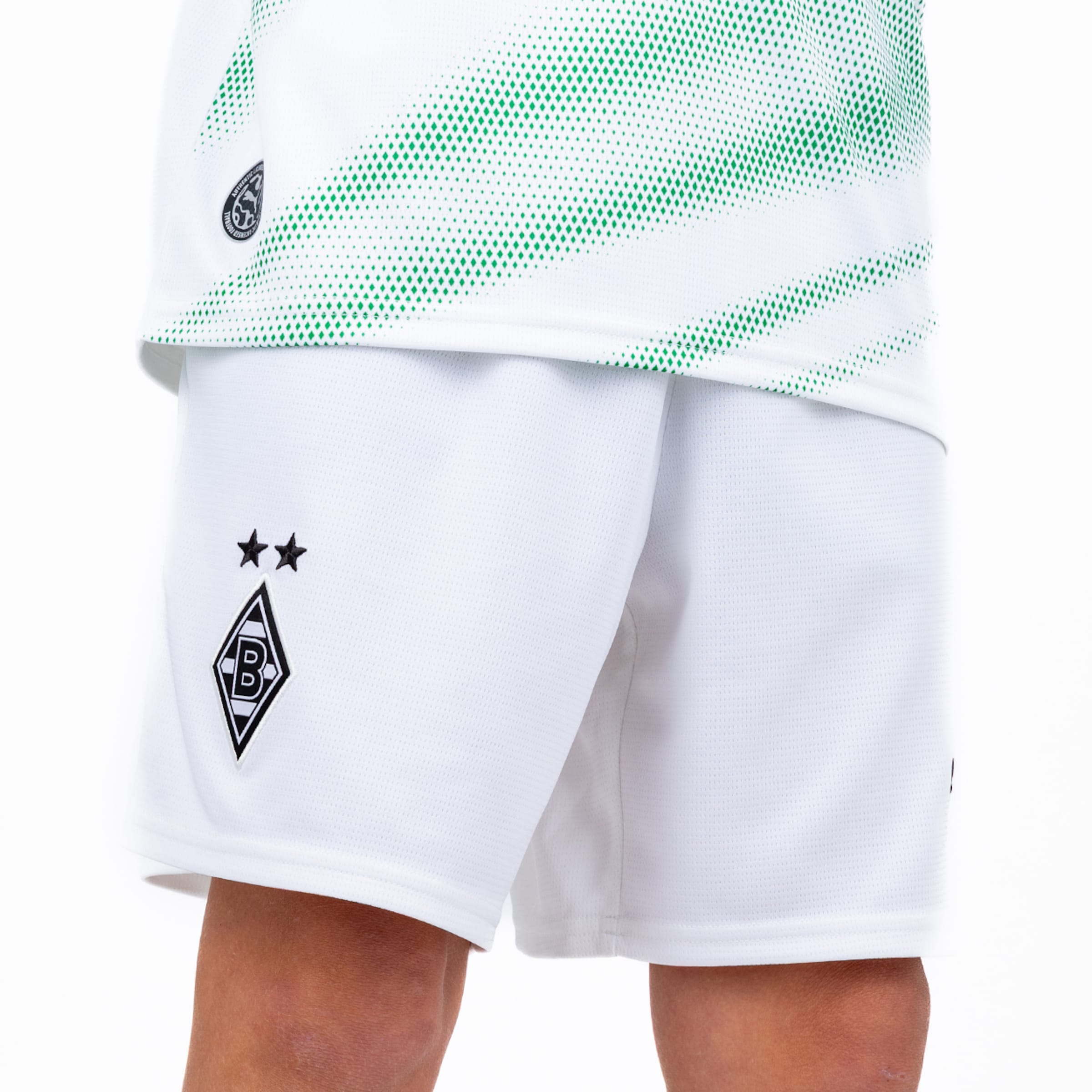 Detailansicht von weiß-grünem Fußballtrikot und weißen Shorts mit dem Logo von Borussia Mönchengladbach und zwei Sternen.