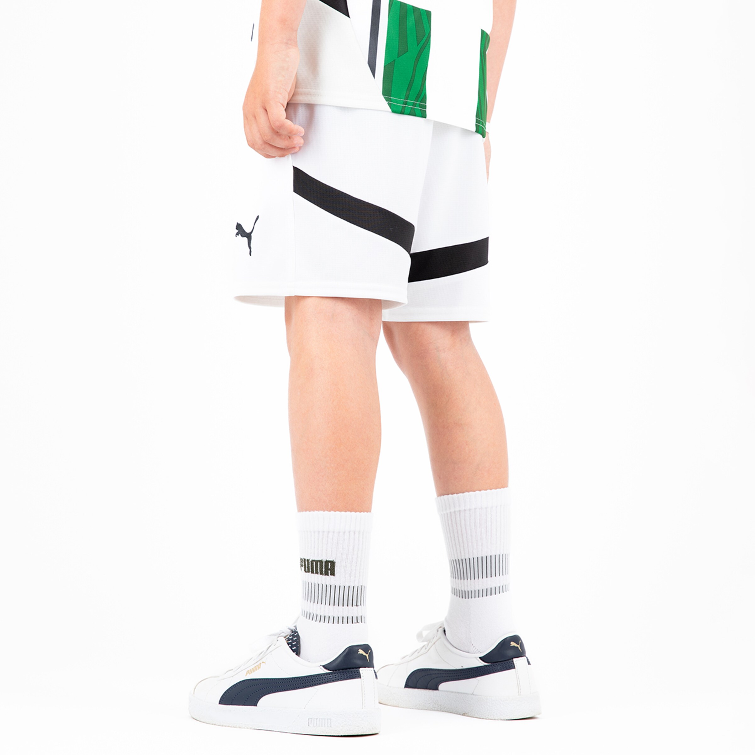 A young athlete stands from behind in white Puma sportswear with colorful details.