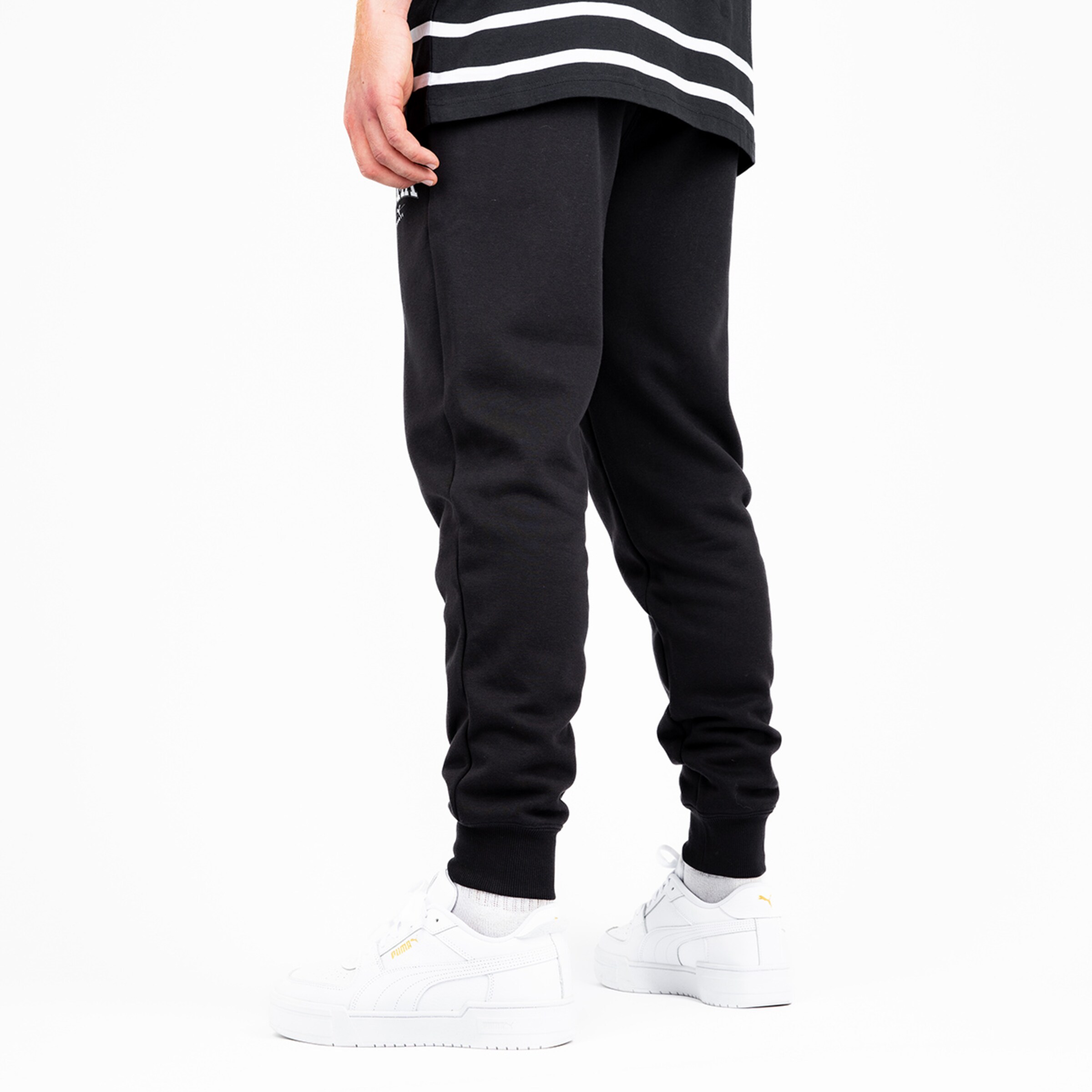 Person wearing black joggers and white sneakers from behind.