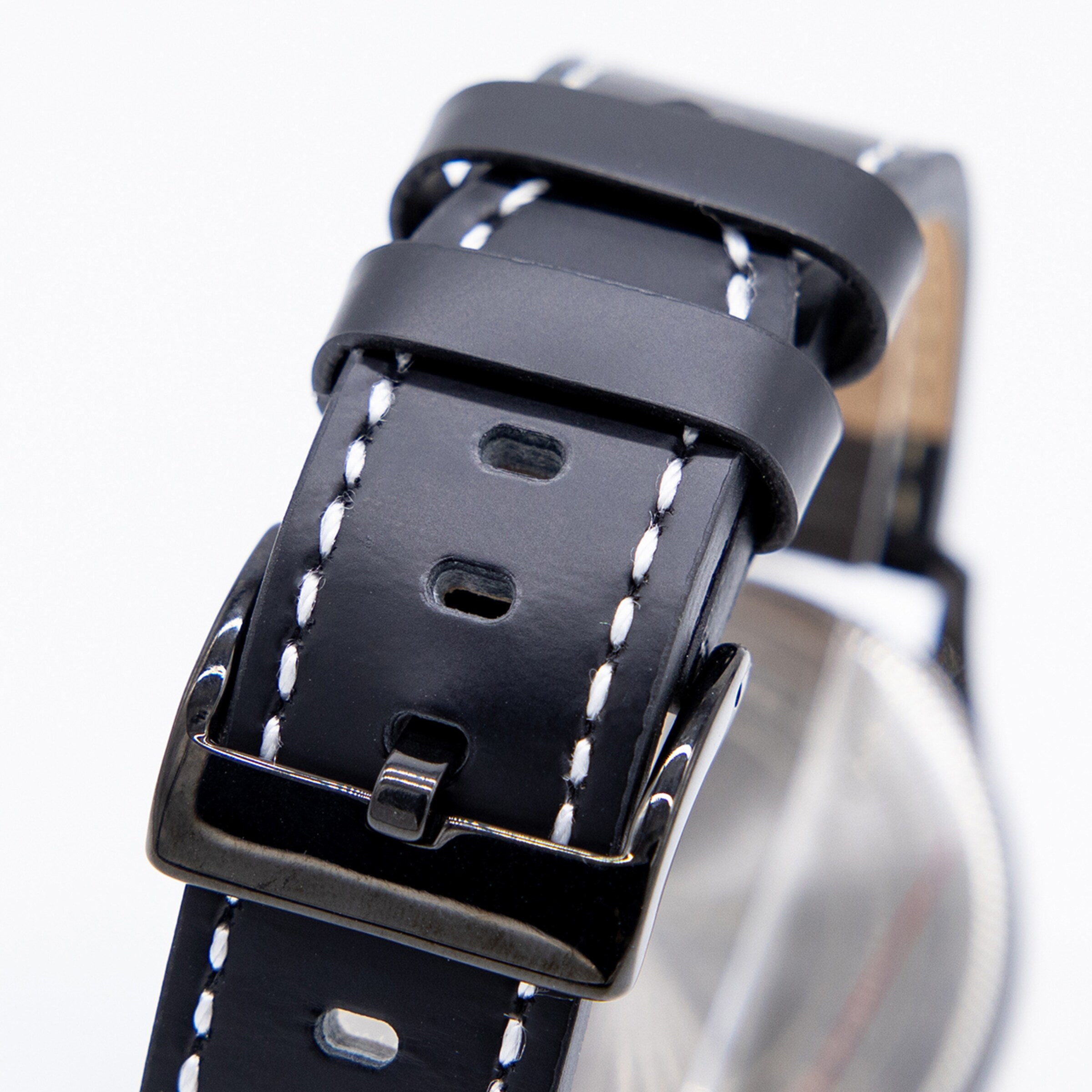 Nahaufnahme eines schwarzen Lederuhrbands mit weißer Kontrastnaht, zwei Schlaufen und schwarzer Dornschließe auf weißem Hintergrund.