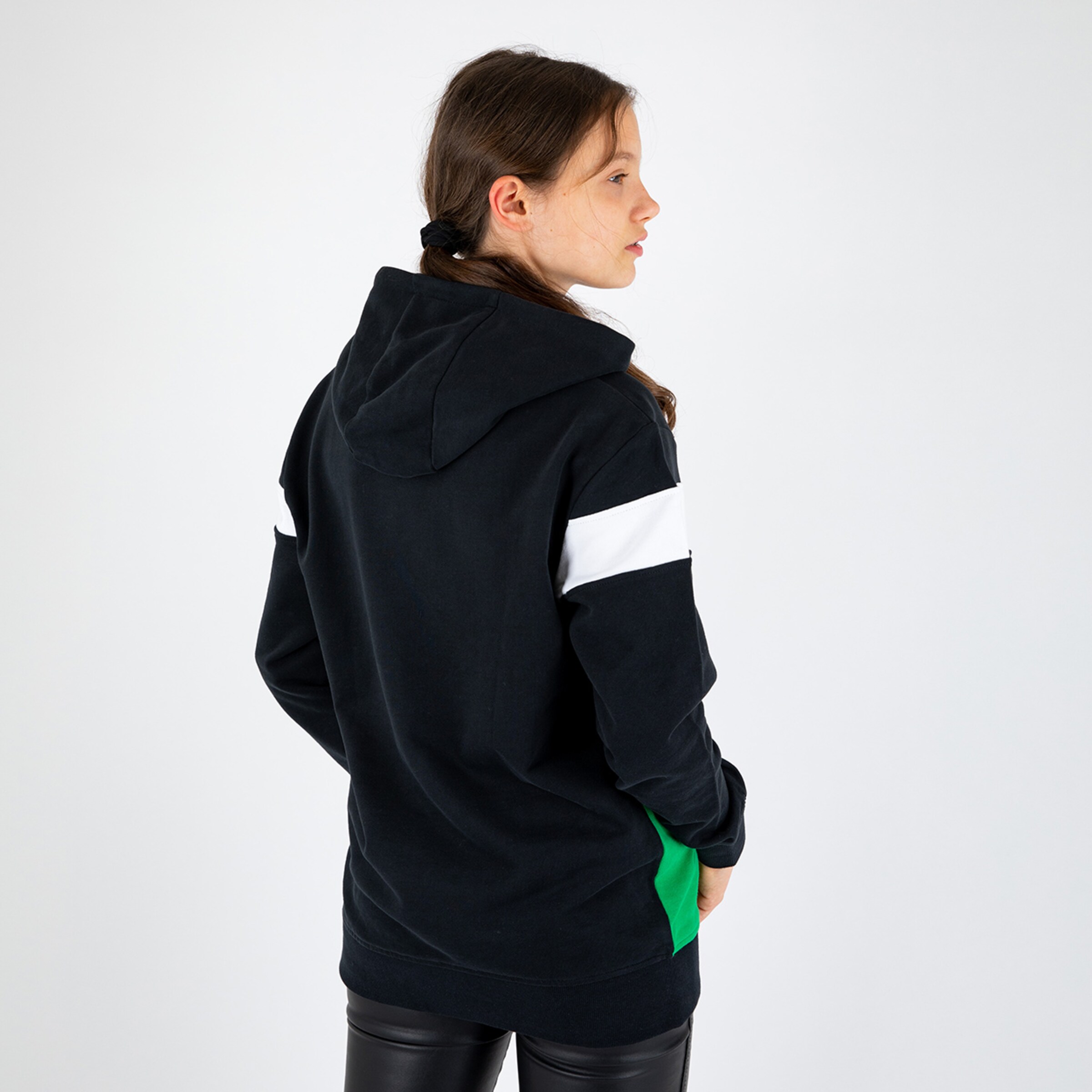 Woman seen from behind wearing a black hoodie with white and green stripes on the sleeves paired with black leggings.