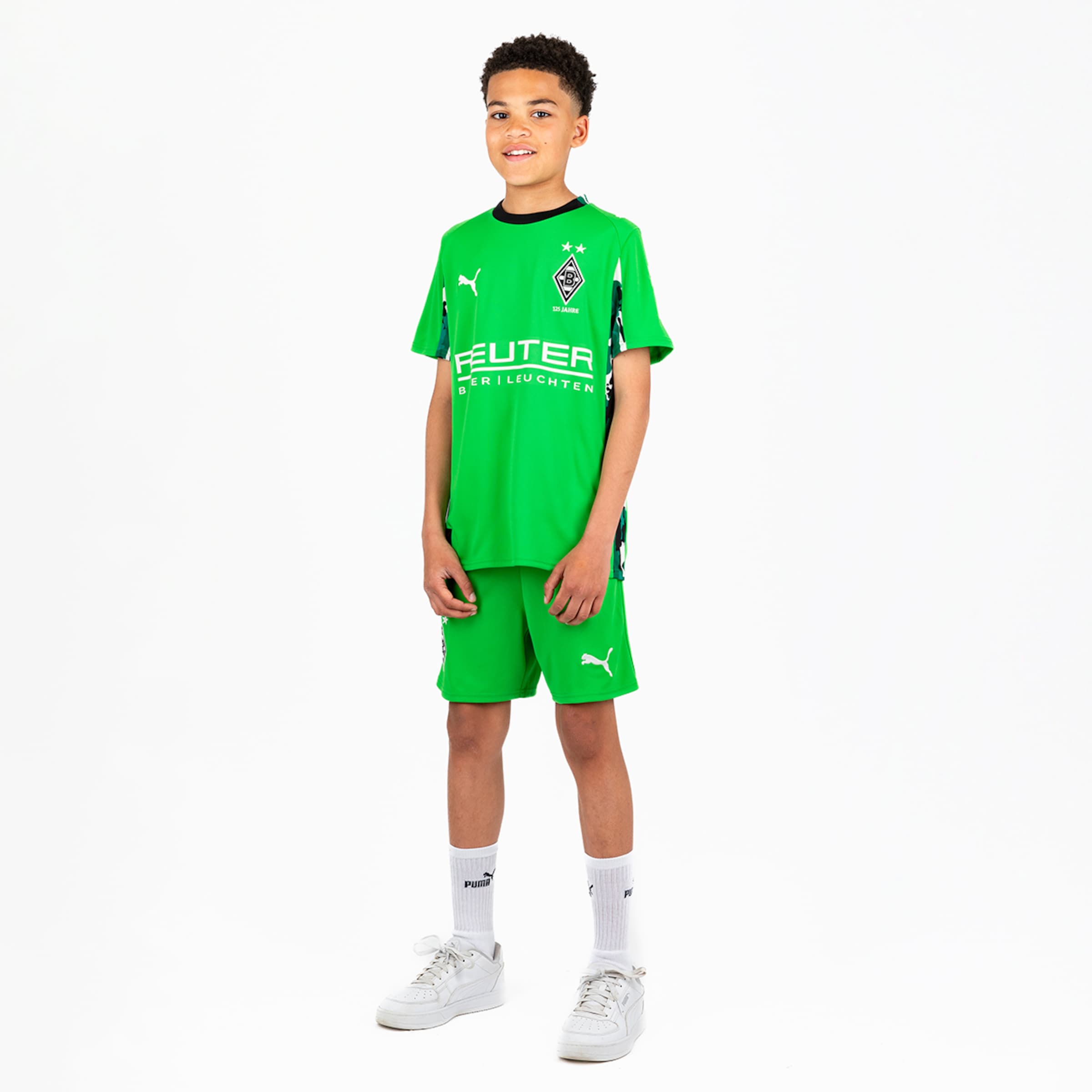 Ein junger Fußballspieler trägt ein grünes Trikot und kurze Hosen von Borussia Mönchengladbach.