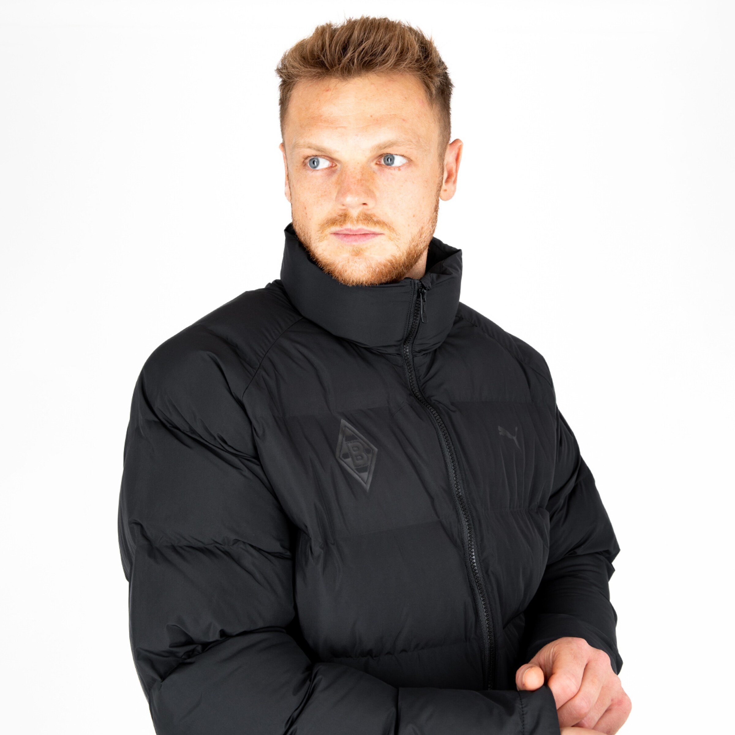 Mann in schwarzer Daunenjacke mit Logo von Borussia Mönchengladbach.