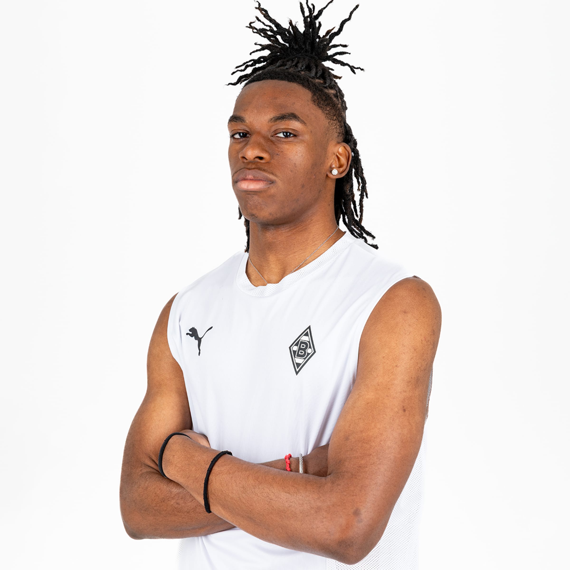 The player poses confidently with crossed arms in a white jersey.