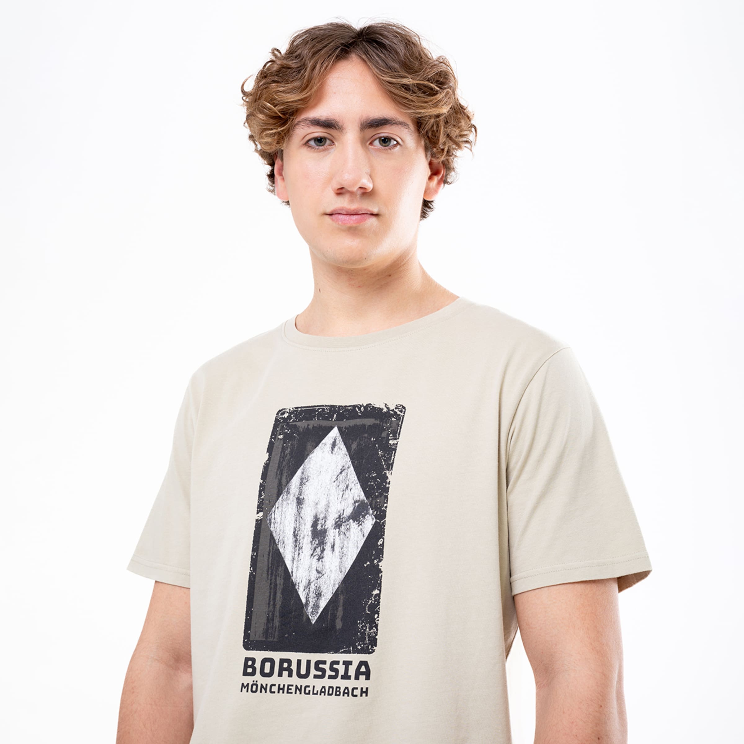 Junger Mann trägt ein hellbeiges T-Shirt mit dem Aufdruck BORUSSIA MÖNCHENGLADBACH und einem Rautensymbol.