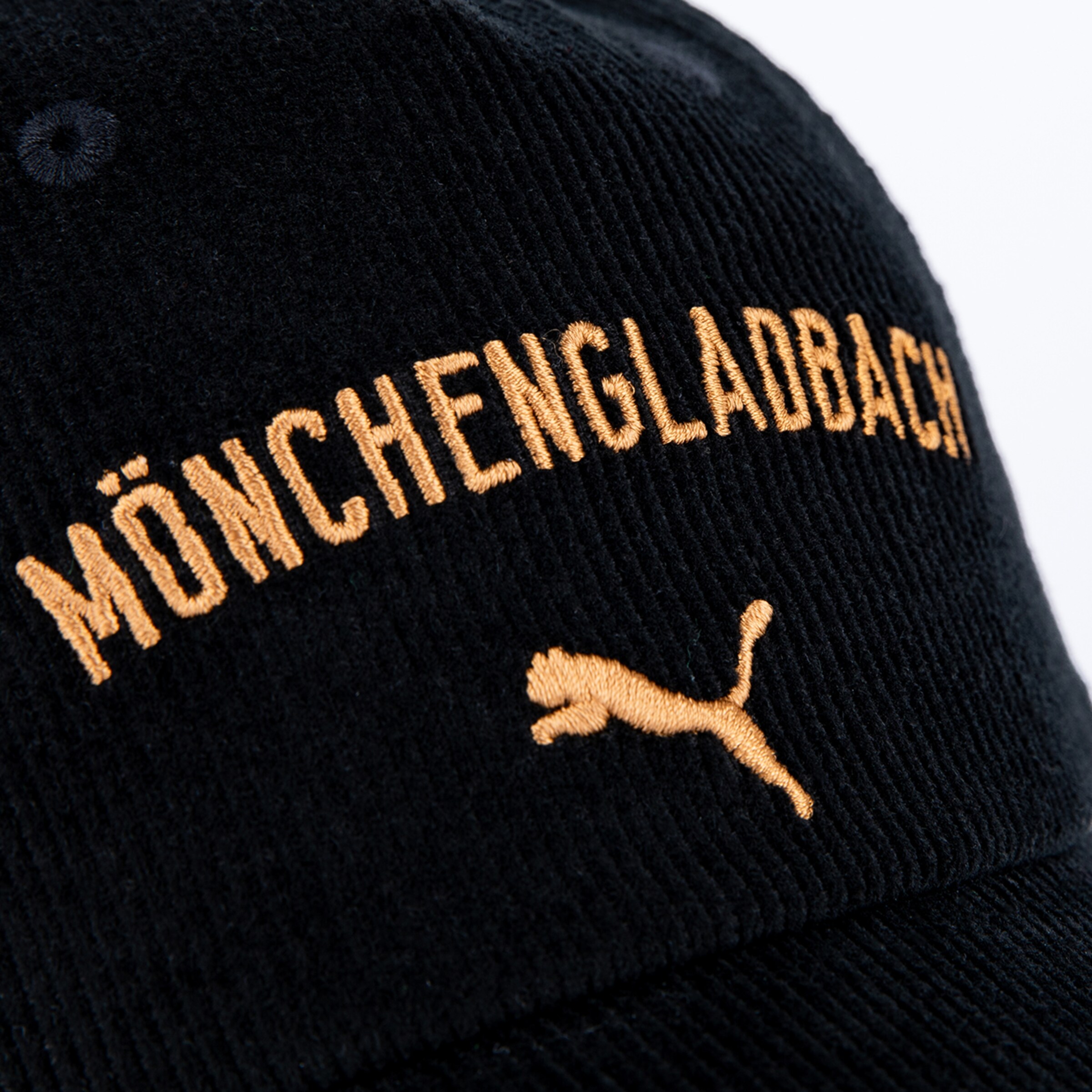 Schwarze Cordmütze mit bogenförmigem, goldfarbenem Stick „MÖNCHENGLADBACH“ und dem springenden Puma-Logo darunter.