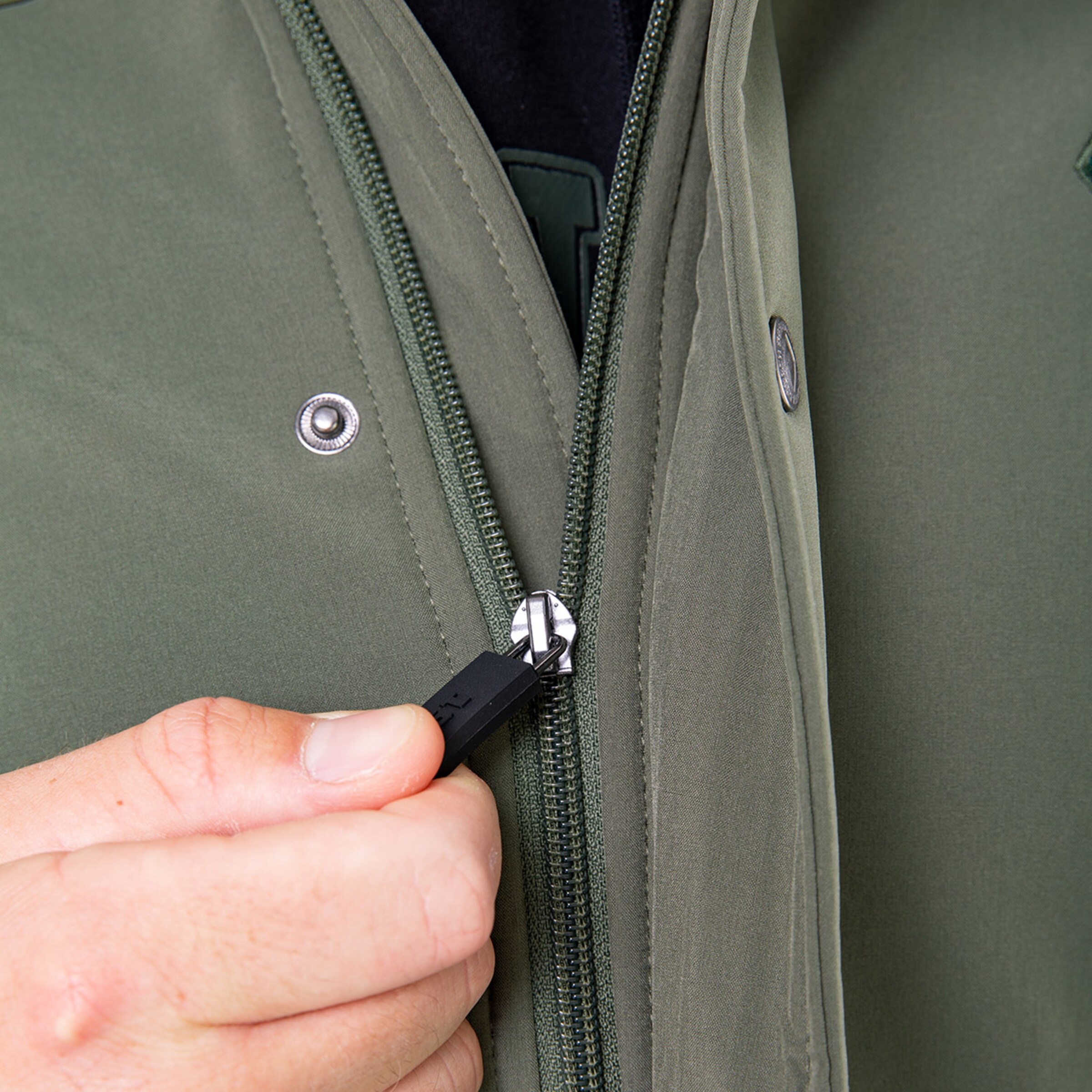 Nahaufnahme eines Mannes der einen grünen Anorak schließt.