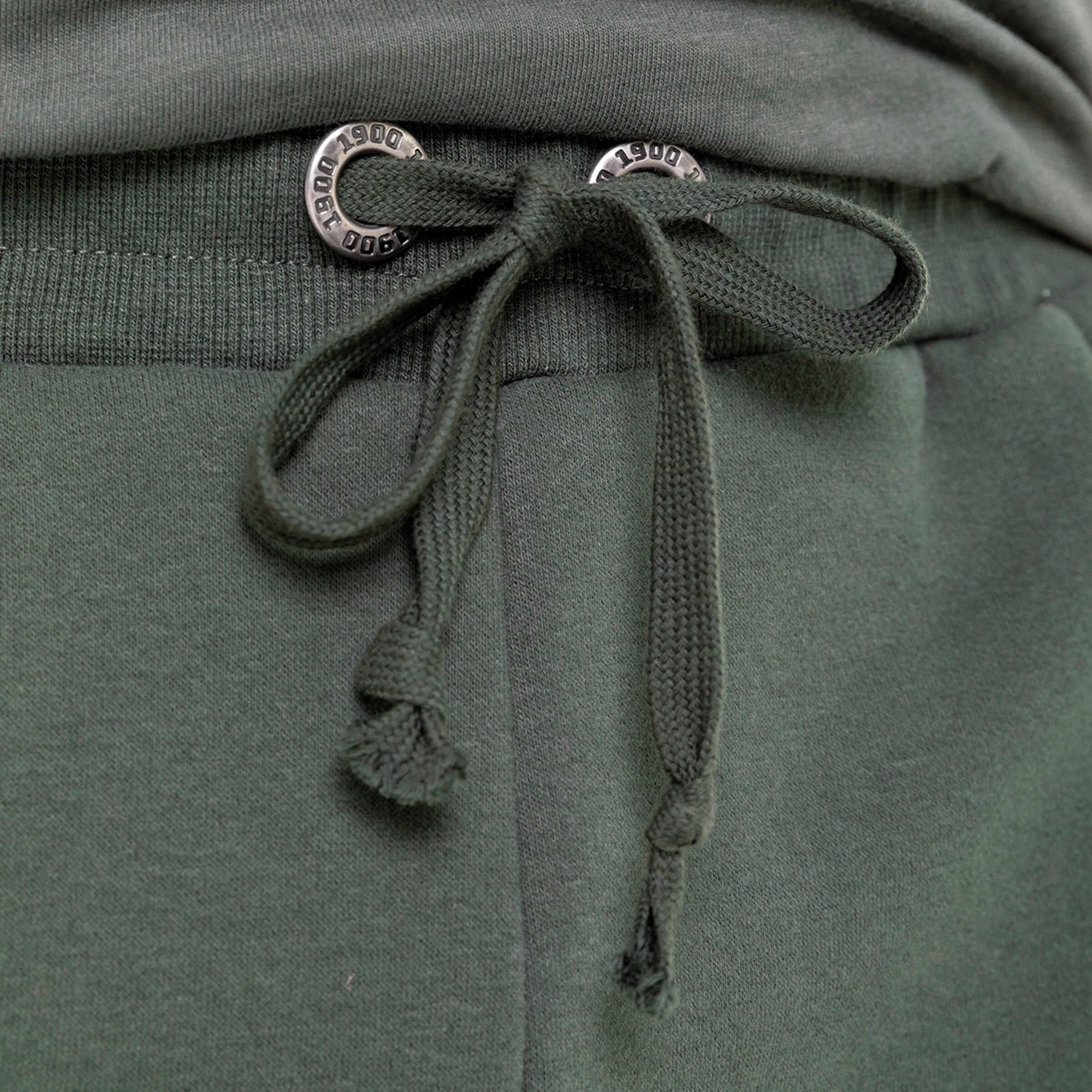 Detailaufnahme des elastischen Bundes und der Kordel einer olivgrünen Jogginghose.