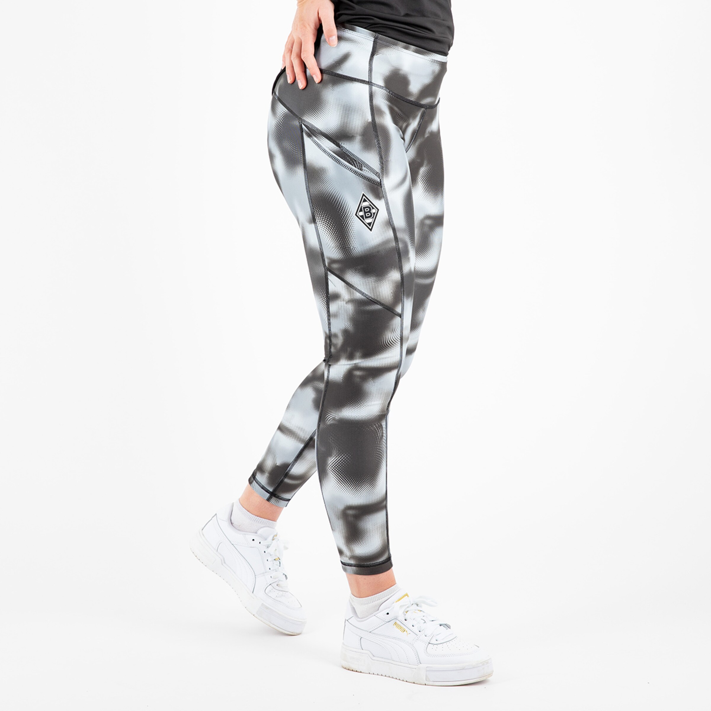 Damen-Leggings mit modernem grafischem Muster in Grau und Schwarz kombiniert mit weißen Sneakers.