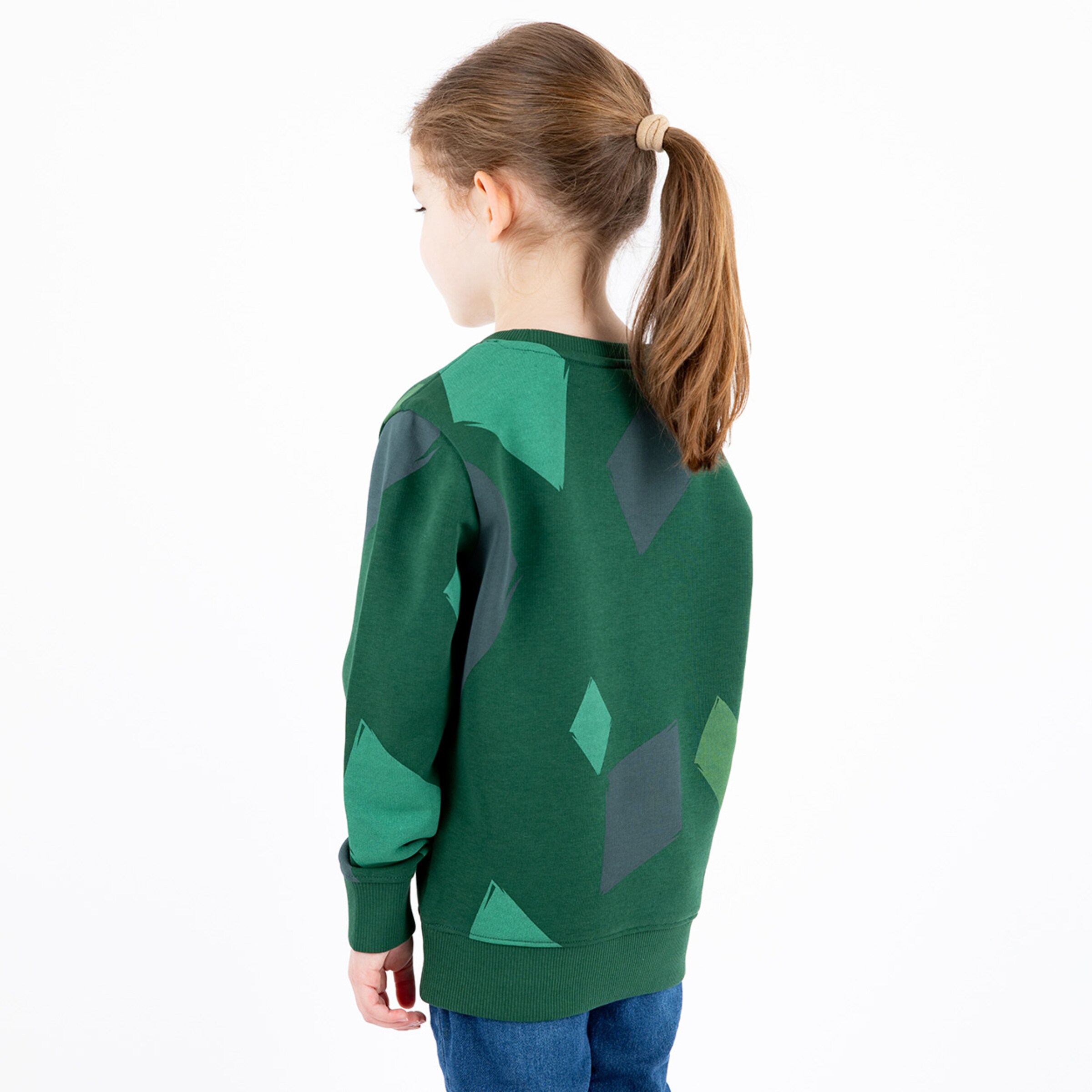 Grüner Sweatshirt mit geometrischen Mustern auf der Rückseite getragen von einem Mädchen mit Pferdeschwanz.