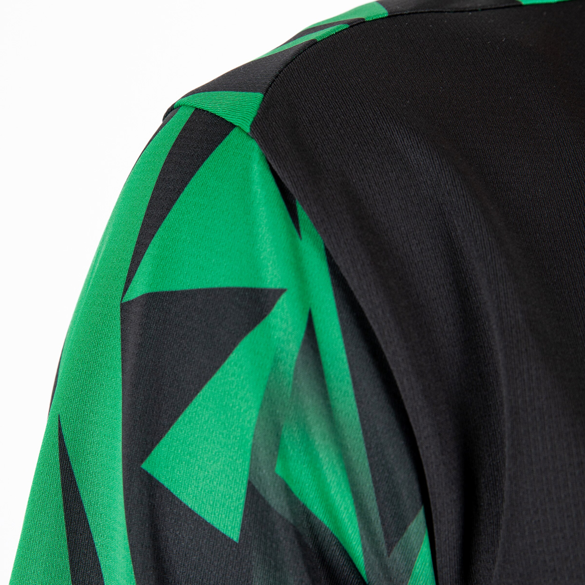 Detailaufnahme eines Trikots in Schwarz und Grün mit geometrischem Muster.