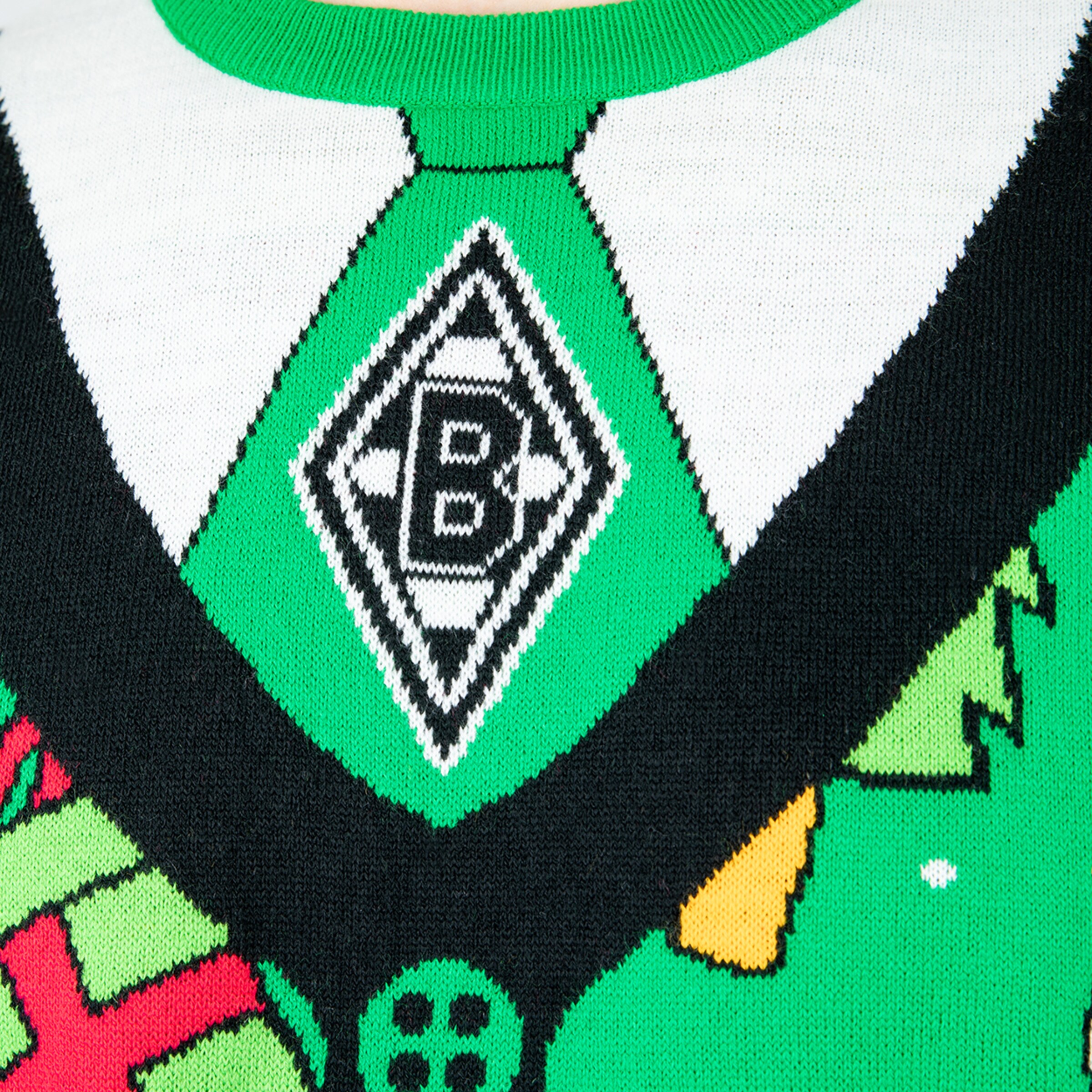 Detailansicht eines grünen Pullovers mit einem Vereinslogo von Borussia Mönchengladbach und weihnachtlichen Motiven.