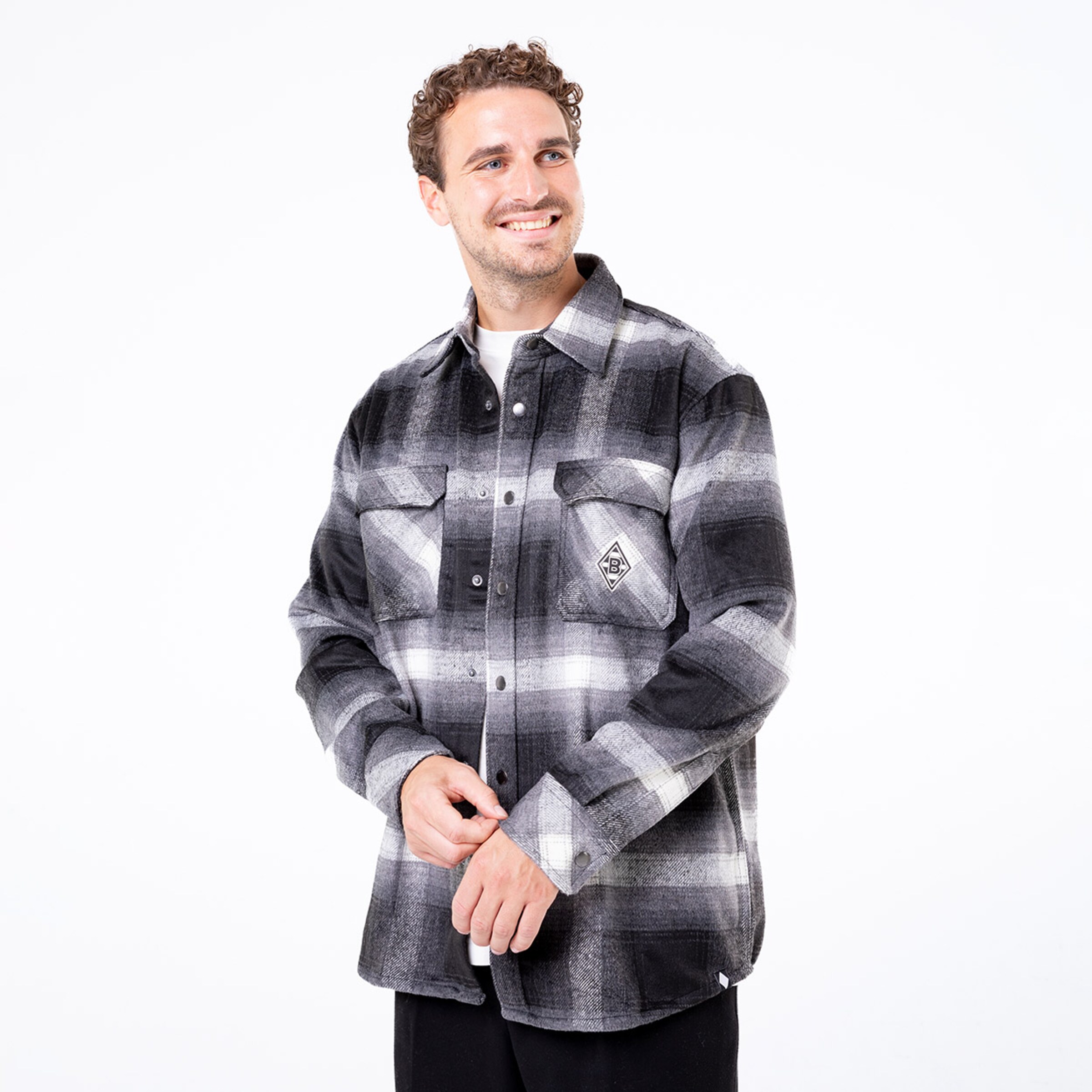 Mann trägt ein kariertes Hemd mit zwei Brusttaschen und lächelt.