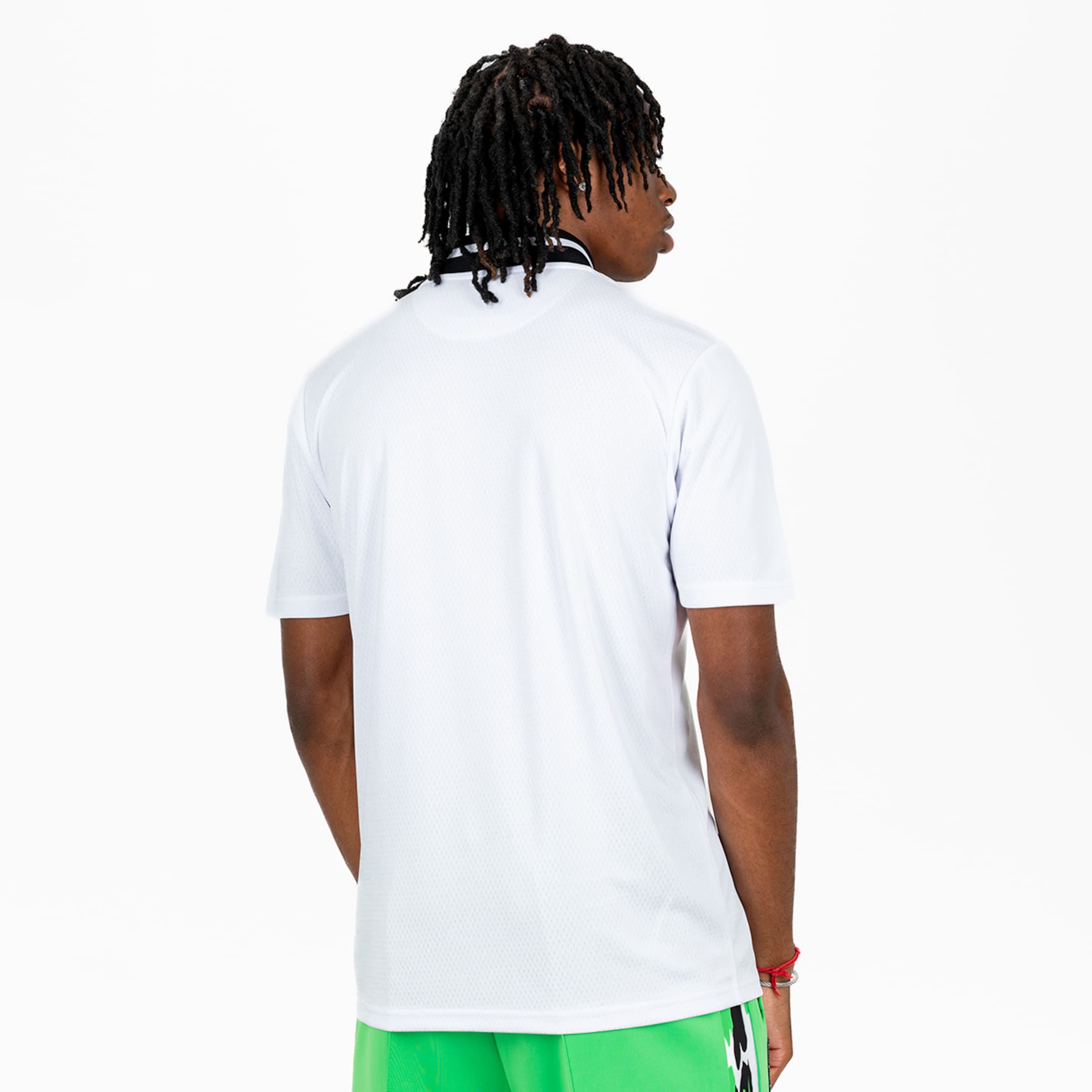 Ein junger Mann von hinten trägt ein weißes Sporttrikot und grüne Shorts.