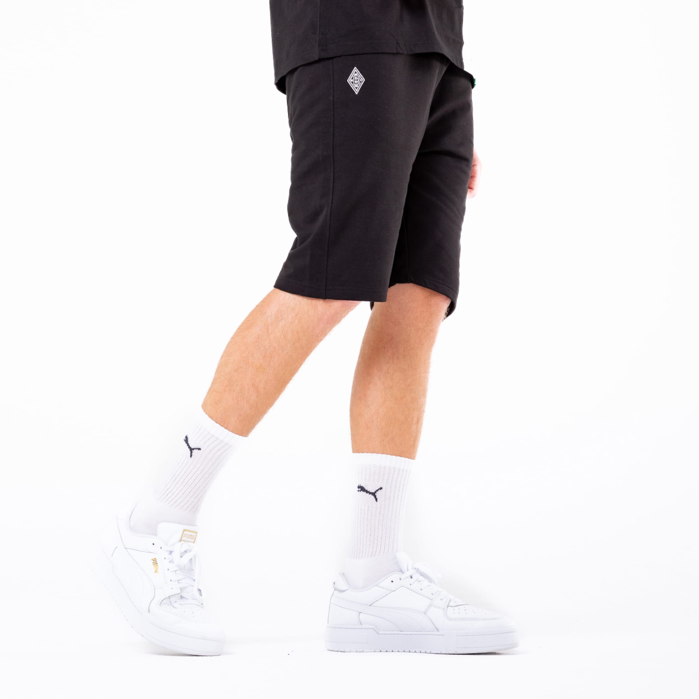 Schwarze Sportshorts mit weißen Socken und Schuhen in einem schlichten Hintergrund.