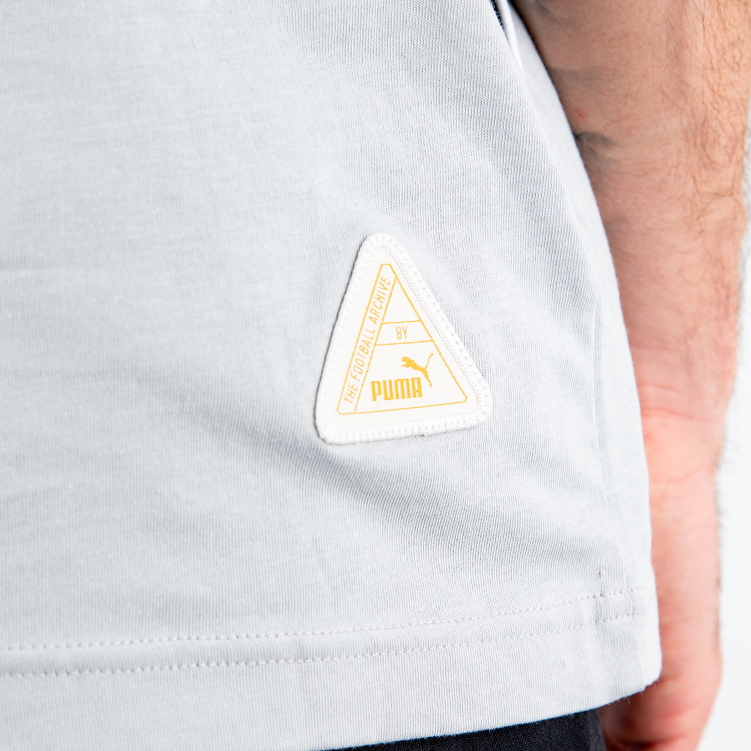 Graues T-Shirt mit einem PUMA-Logo-Label auf der Seite.