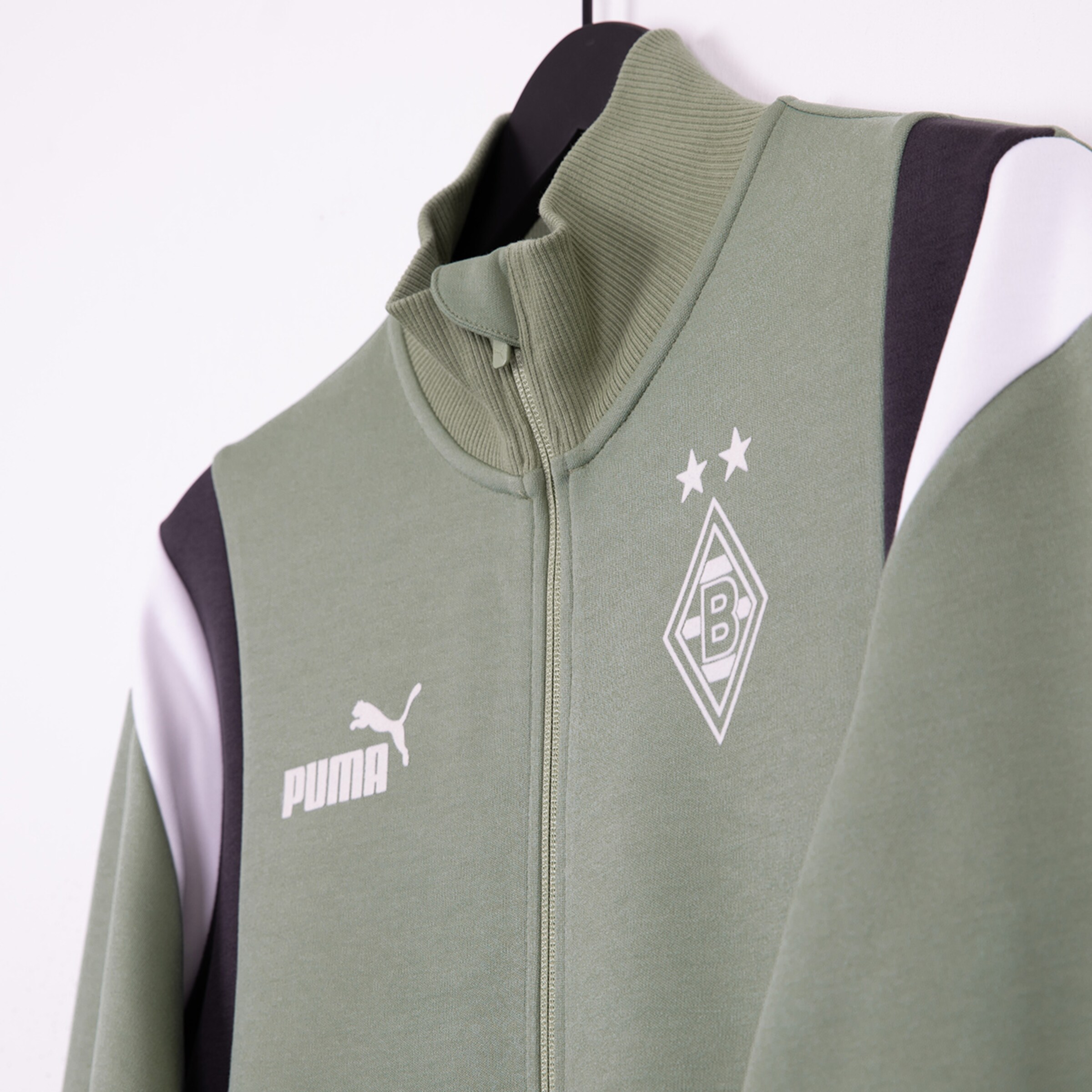 Sportjacke in Olivgrün mit Puma-Logo und Borussia Mönchengladbach-Wappen.