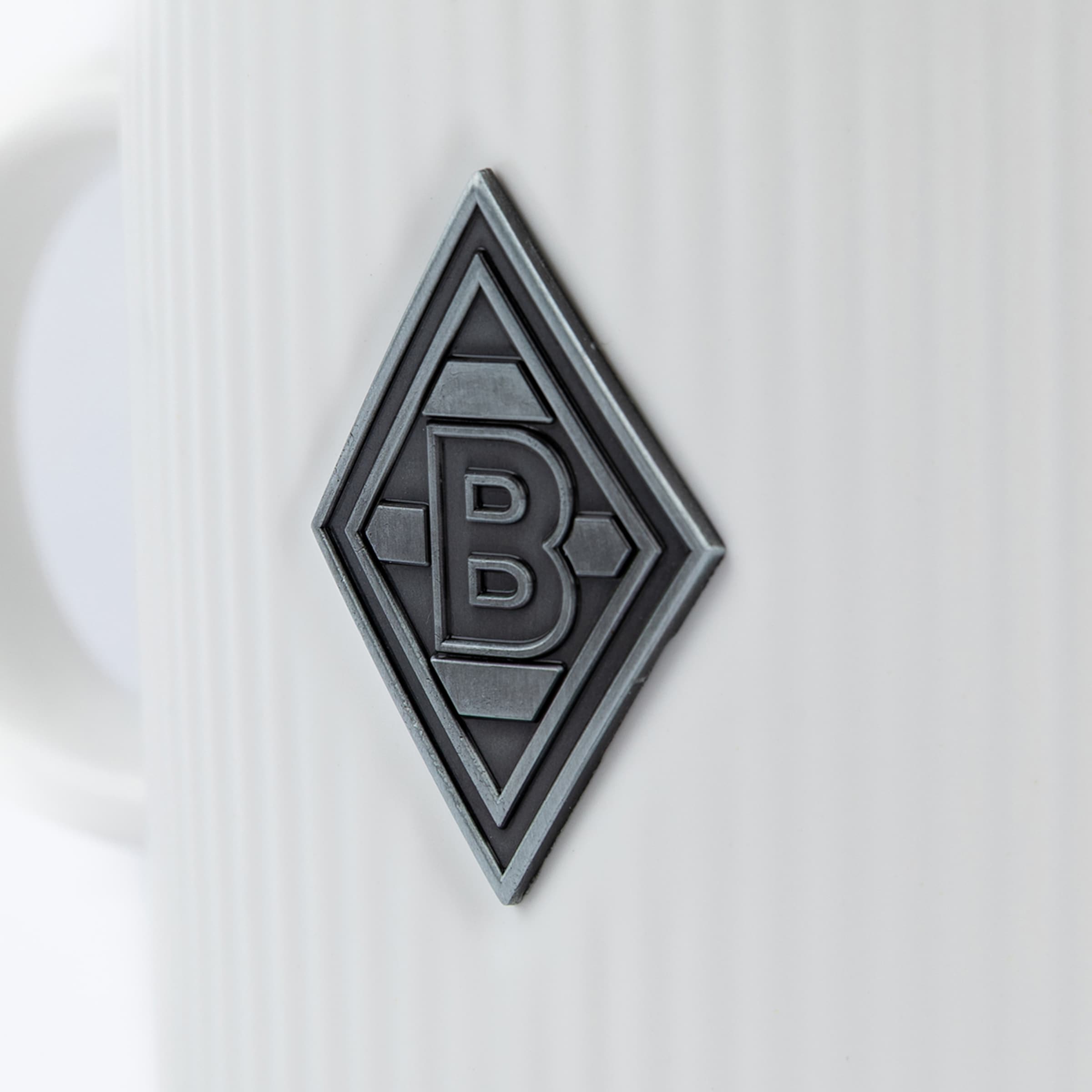 Graue Tasse mit Relief eines rautenförmigen Borussia Mönchengladbach-Logos.