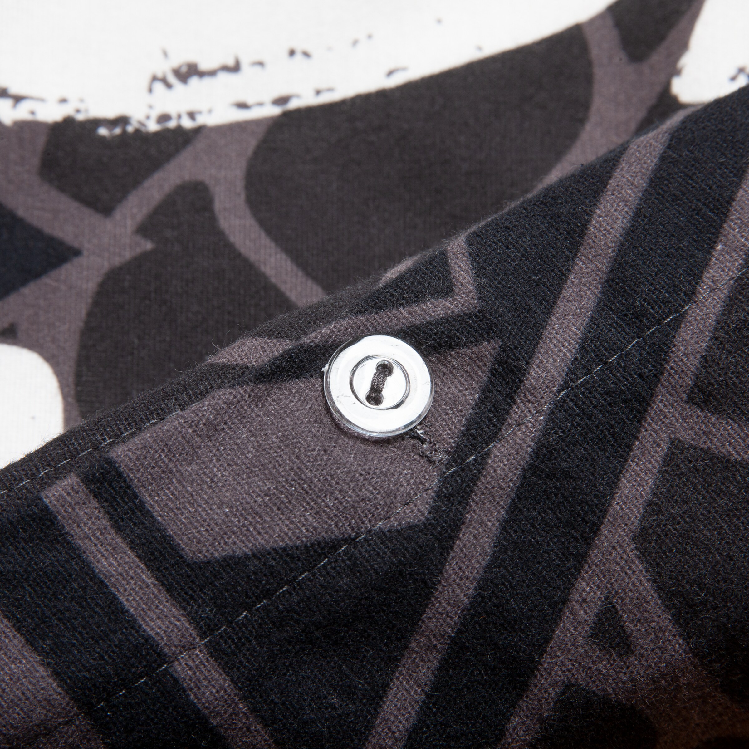 Detailaufnahme eines schwarzen T-Shirts mit Druck und Knopf.