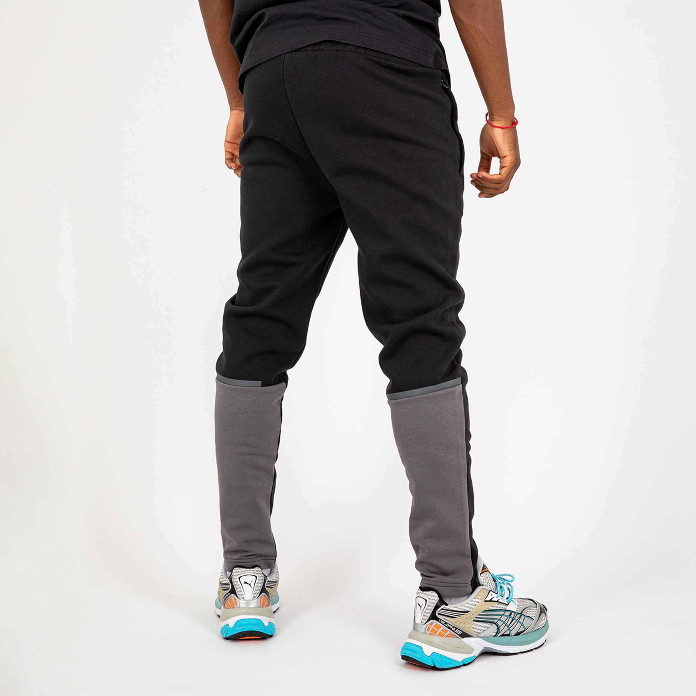 Ein Mann in Sportbekleidung von hinten trägt schwarze Jogginghosen und Sneakers.