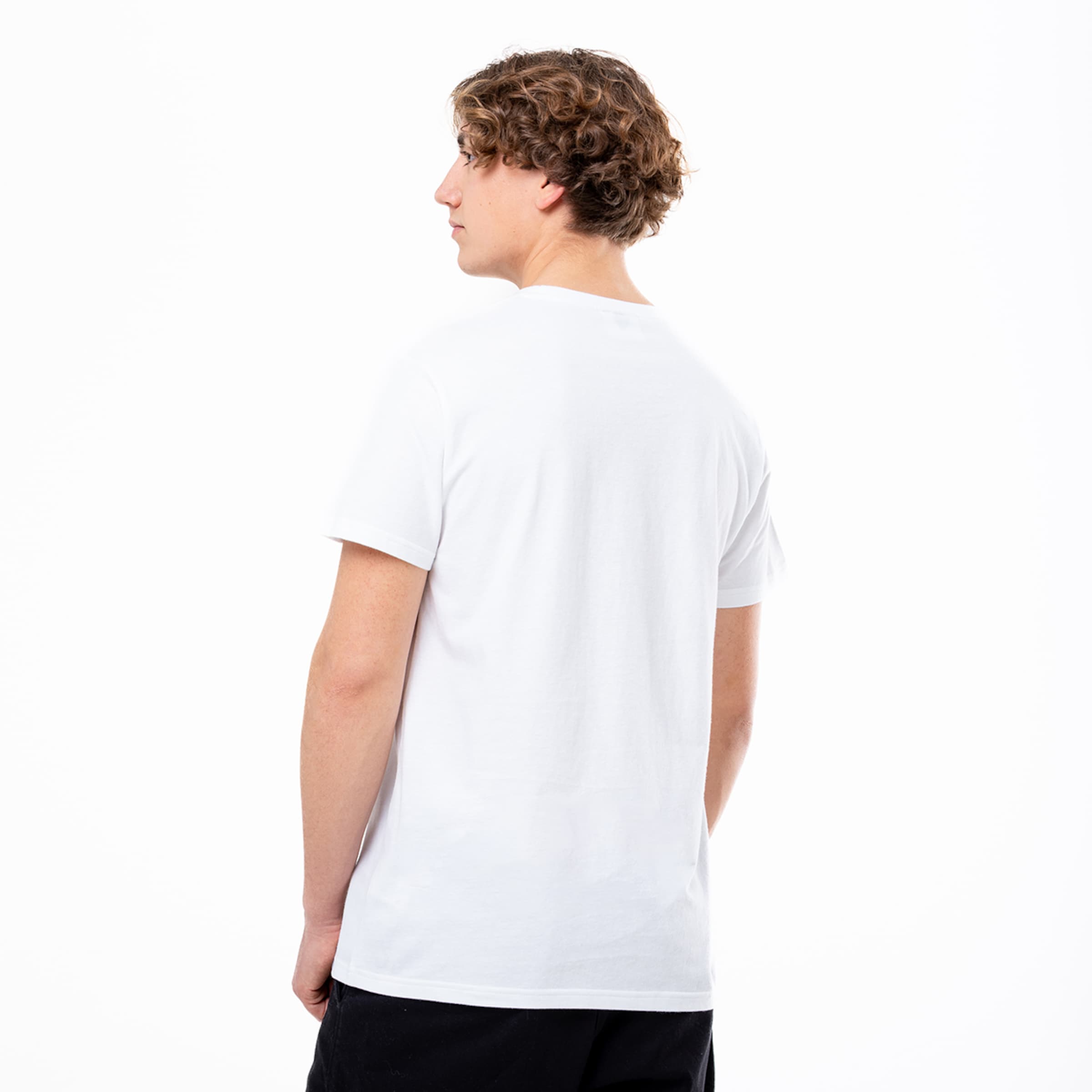 Rückansicht eines jungen Mannes mit lockigem braunem Haar in einem schlichten weißen T-Shirt vor weißem Hintergrund.