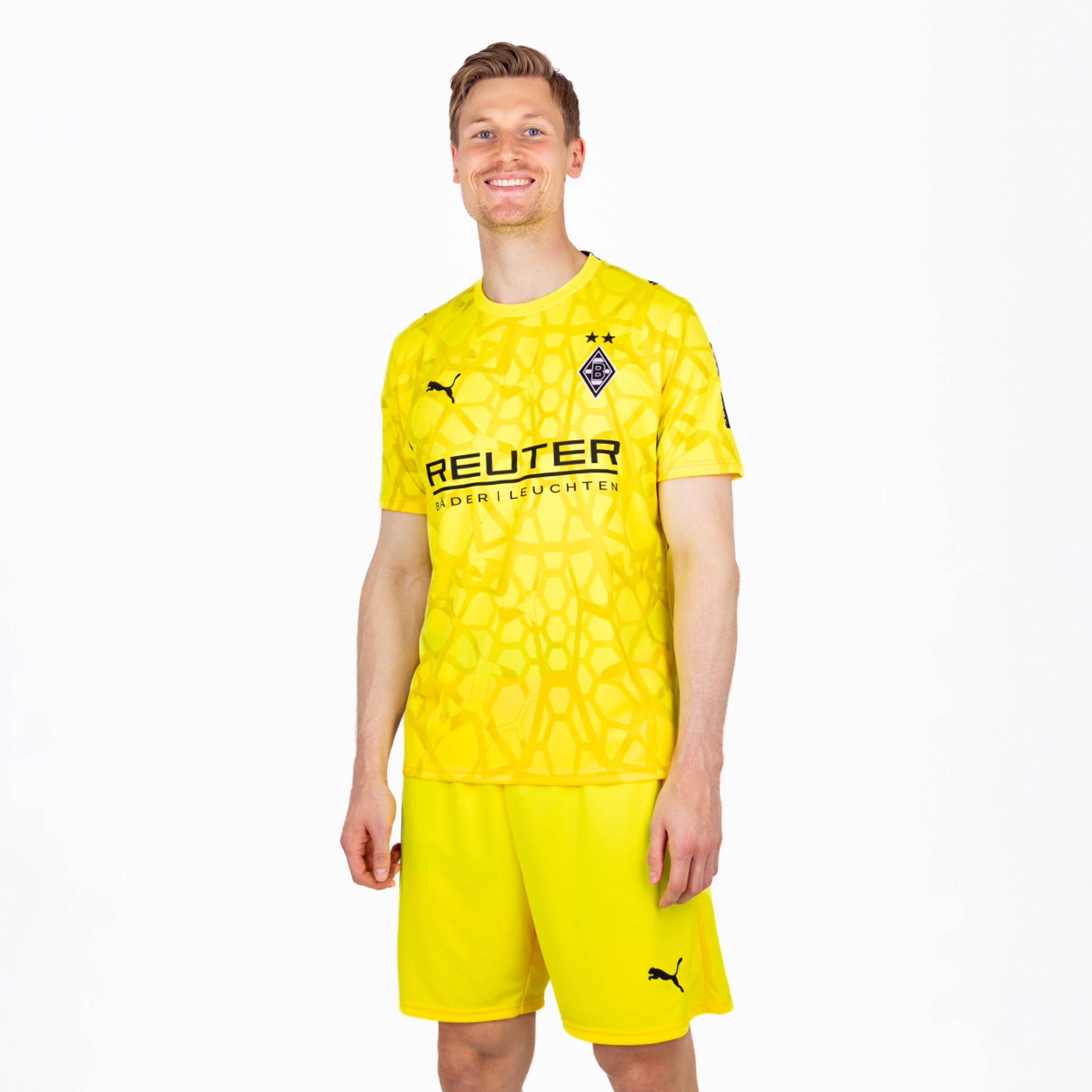 Moritz Nicolas im gelben Borussia Mönchengladbach Torwartset mit Puma-Logo und Reuter-Sponsor vor weißem Hintergrund.