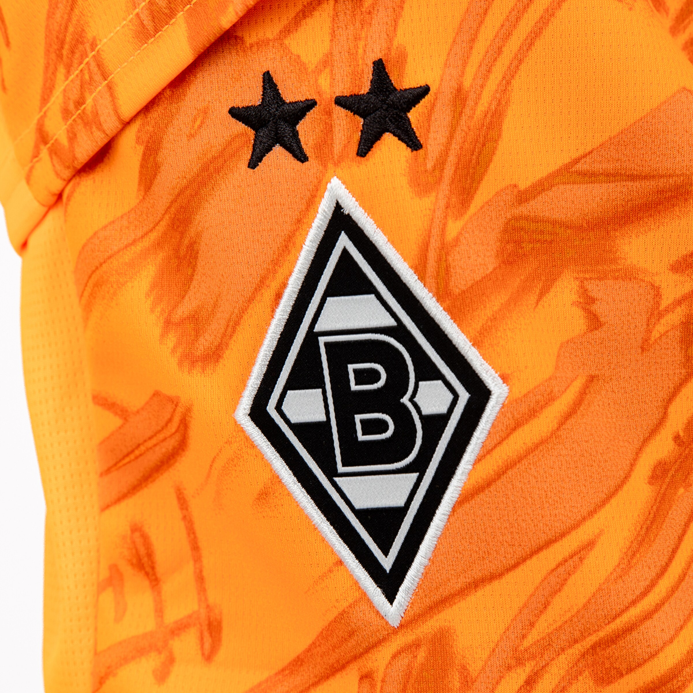 Detailansicht des Borussia Mönchengladbach Vereinswappens auf einem orangefarbenen Trikot.