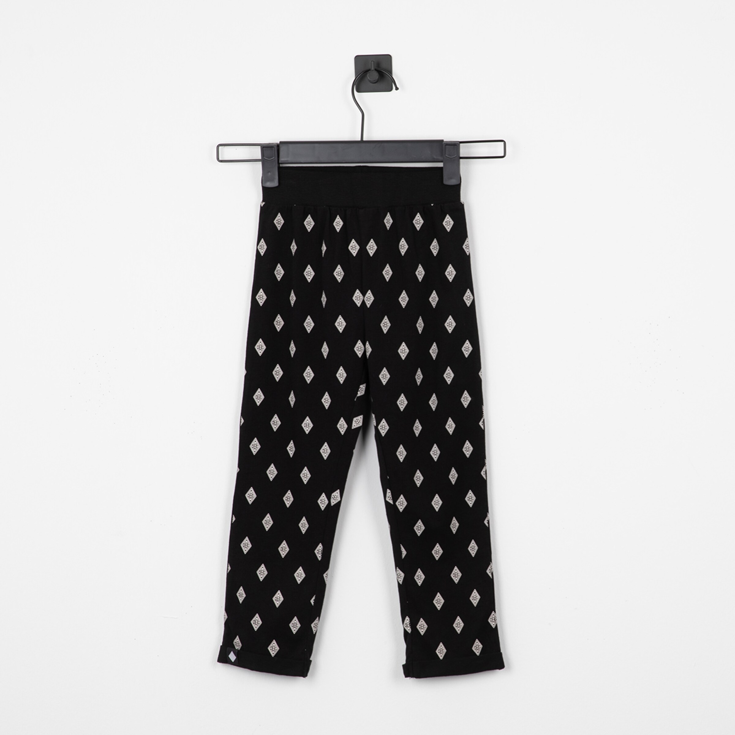 Schwarze Leggings mit silbernen rhombischen Mustern auf einem Haken hängend.