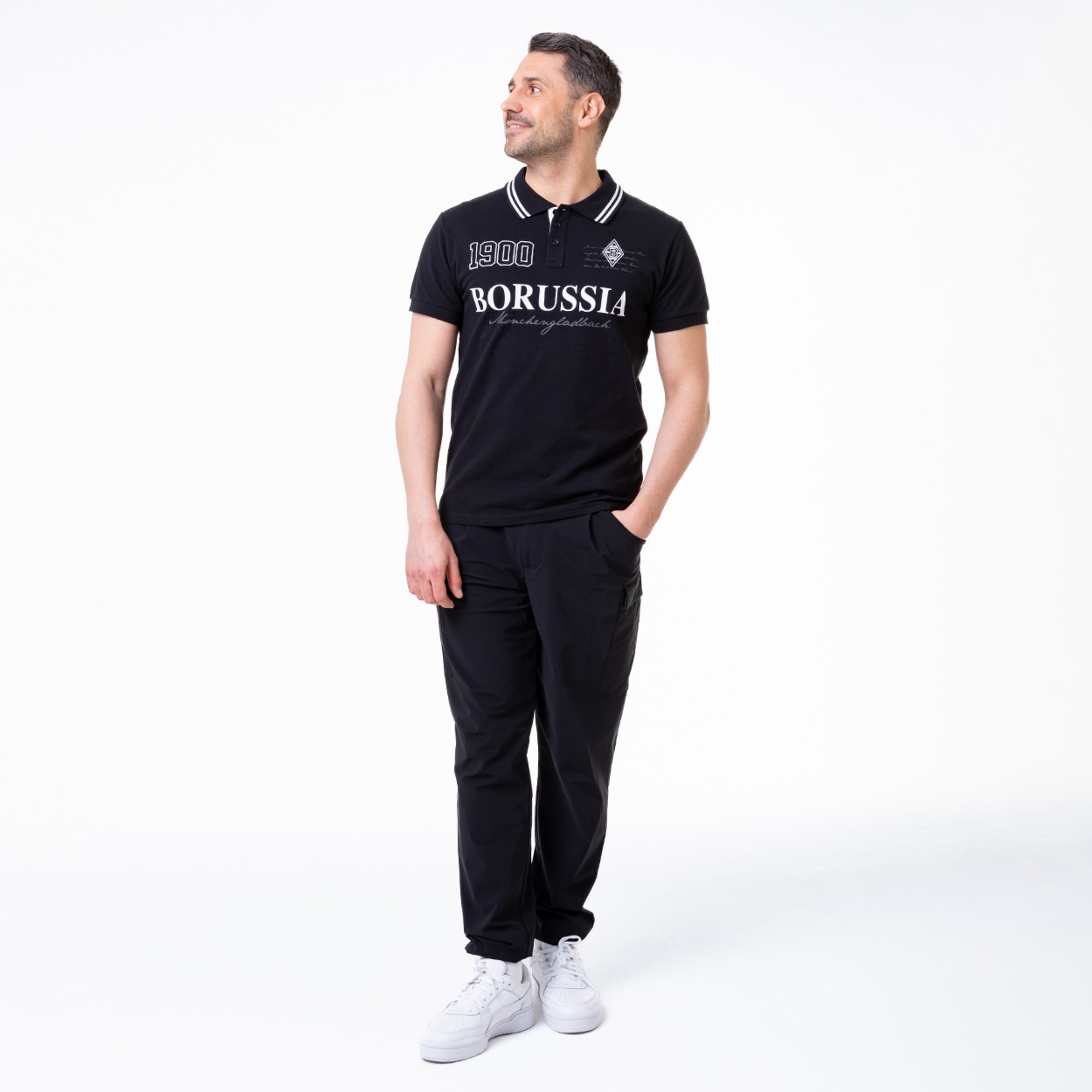 Mann in schwarzem Polo mit BORUSSIA-Aufschrift und schwarzer Hose.