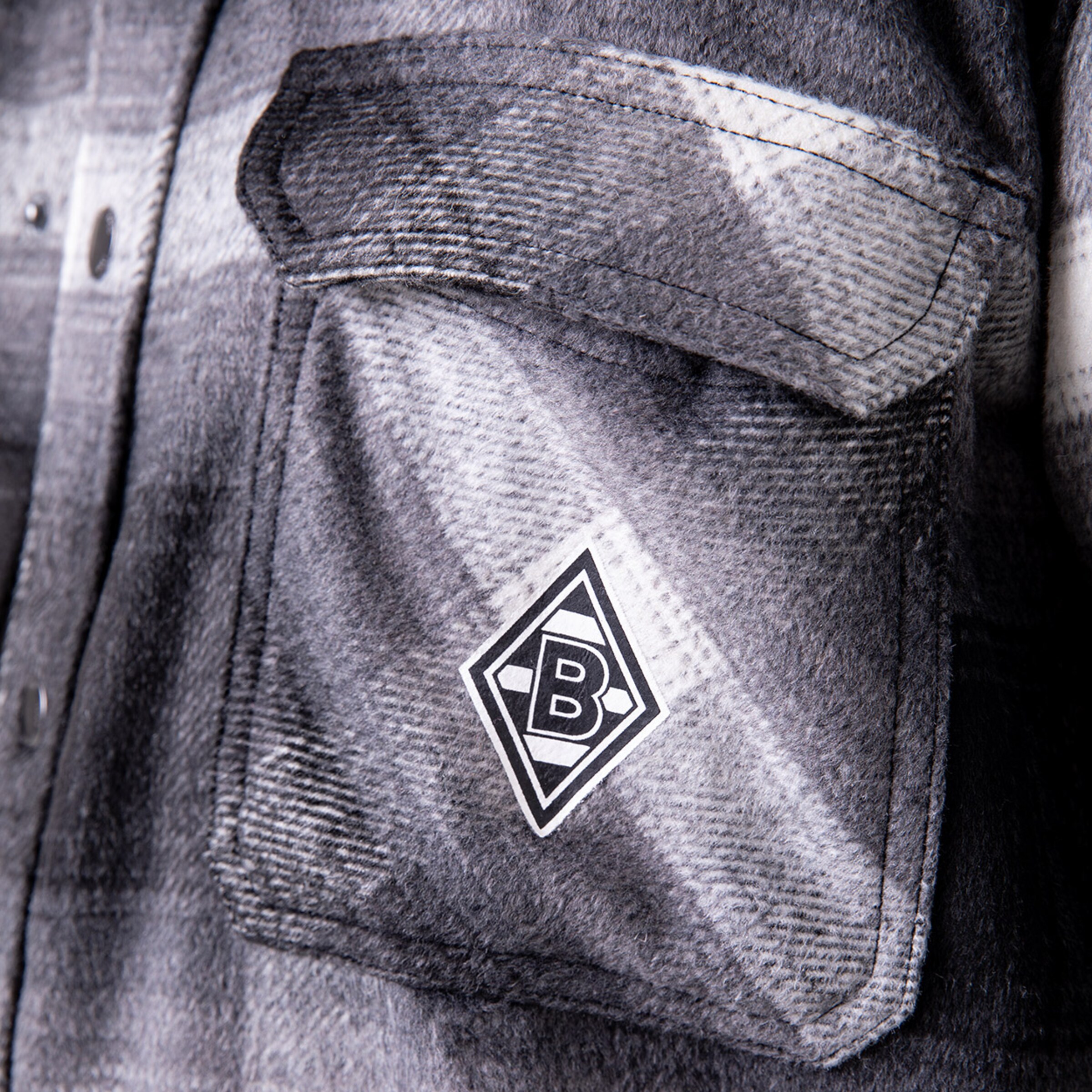 Nahaufnahme einer grauen Jacke mit dem Borussia Mönchengladbach-Logo auf der Brusttasche.
