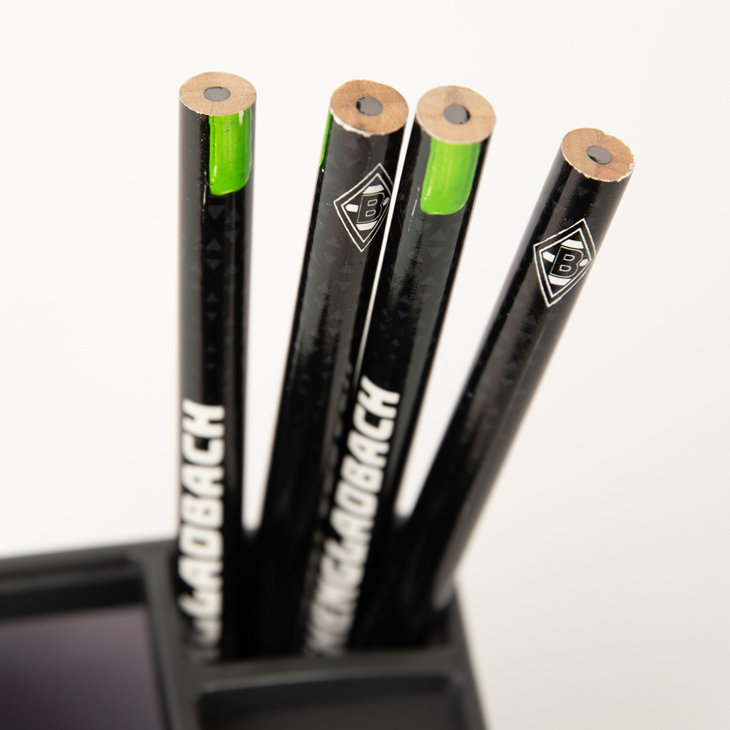 Vier schwarze Bleistifte mit grünem Ende in einem Behälter stehend.