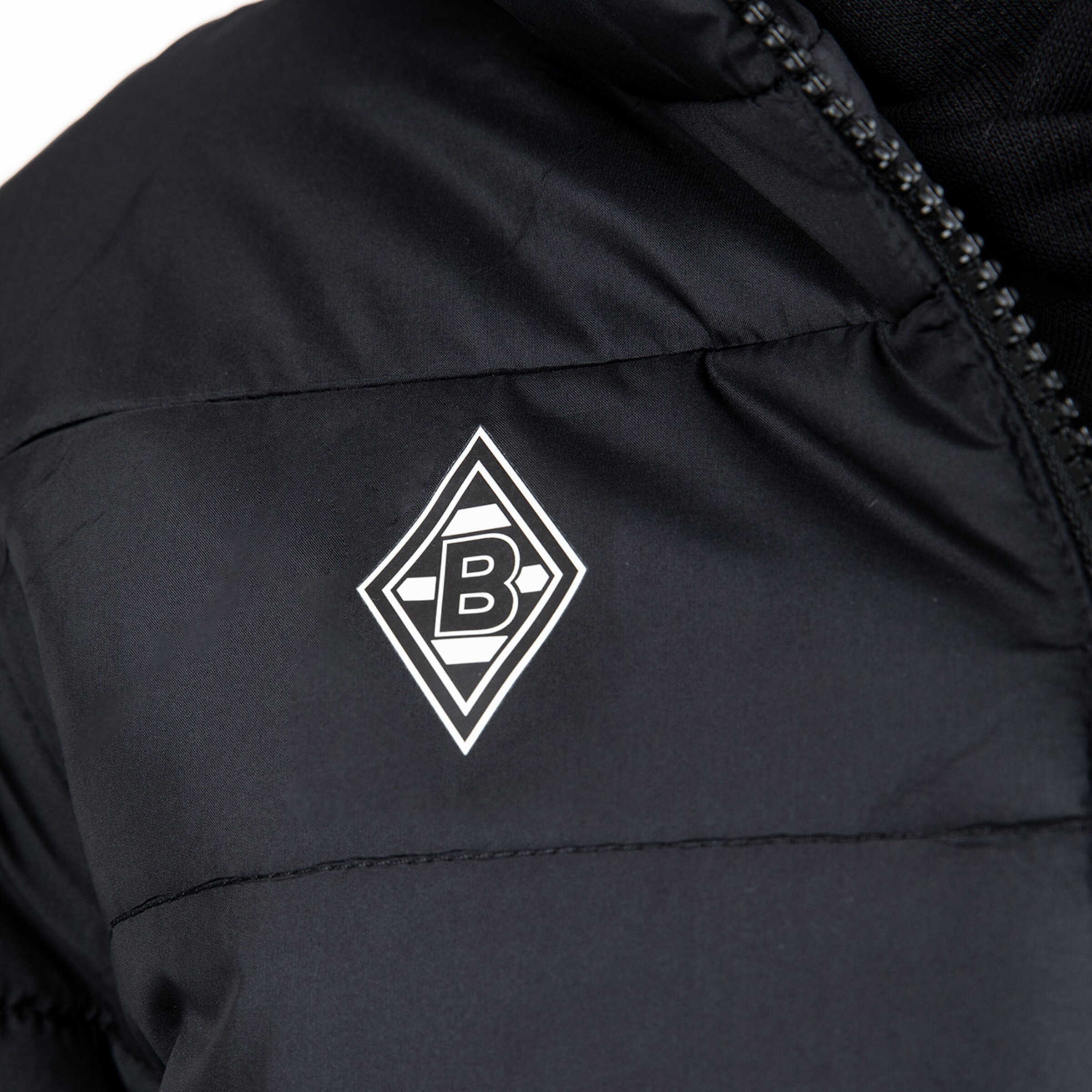 Close-up of a black puffer jacket featuring the Borussia Mönchengladbach logo on the chest.