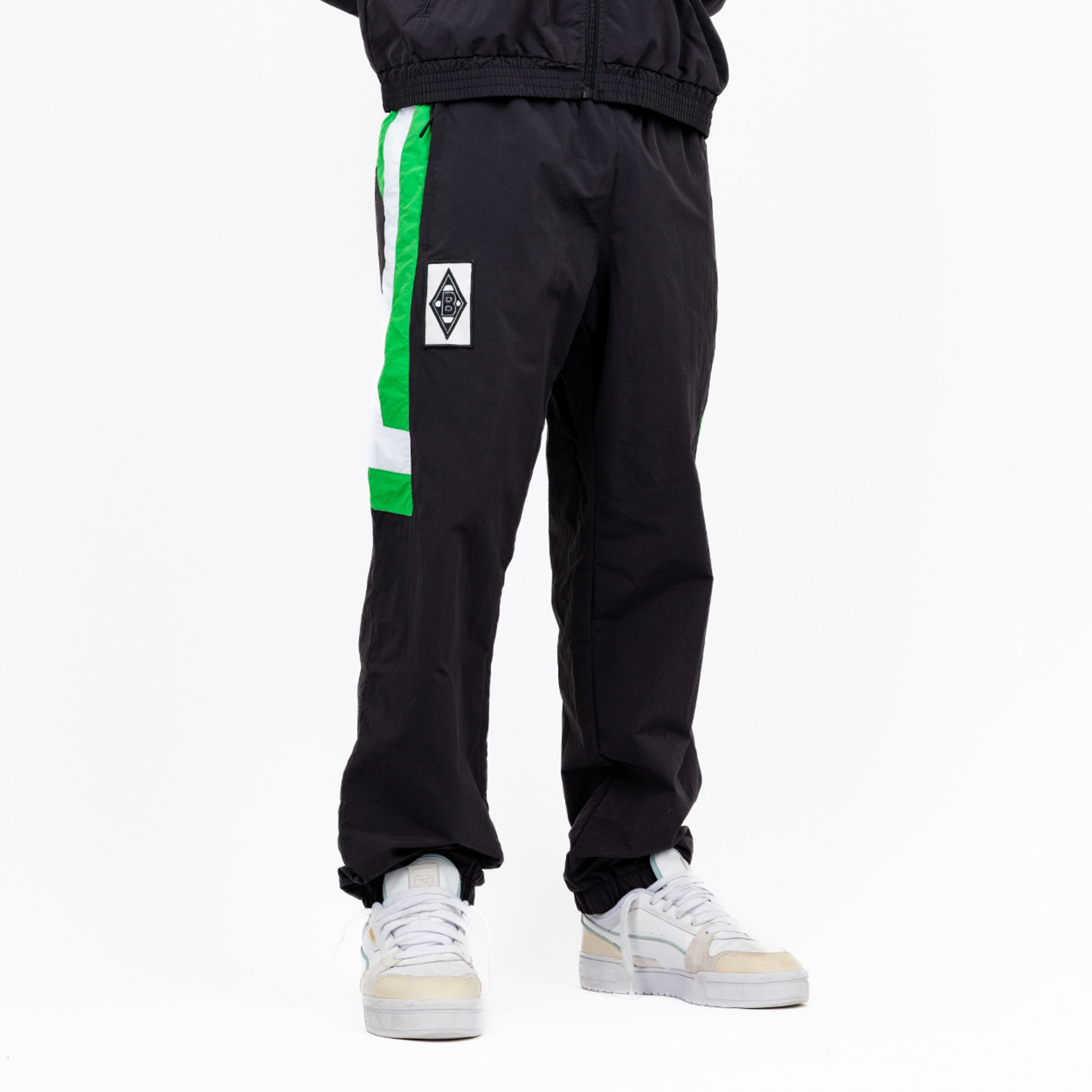 Schwarze Trainingshose von Borussia Mönchengladbach mit grünem Streifen und Logo.
