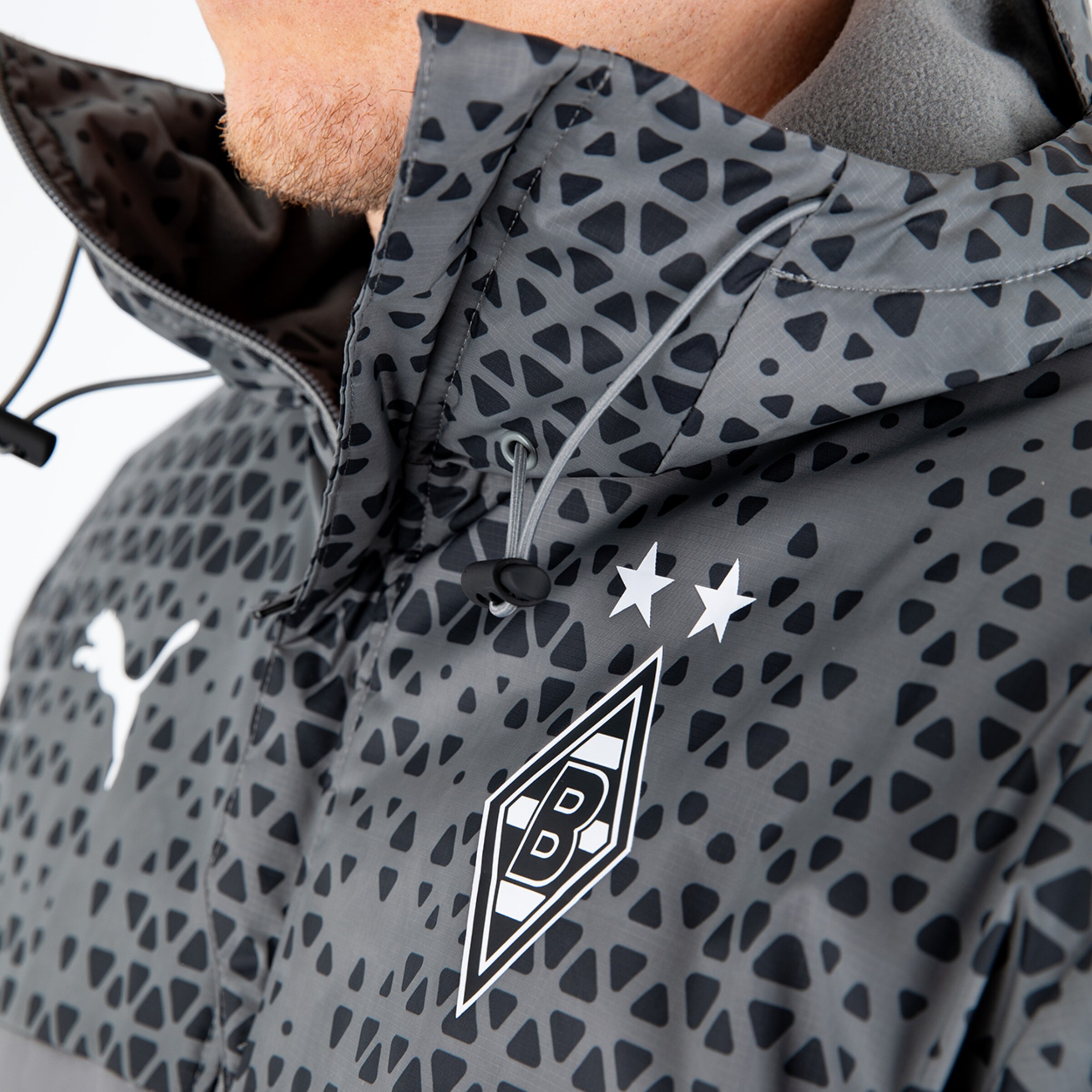 Graue PUMA Jacke mit Borussia Mönchengladbach Logo und zwei Sternen auf der Brust.
