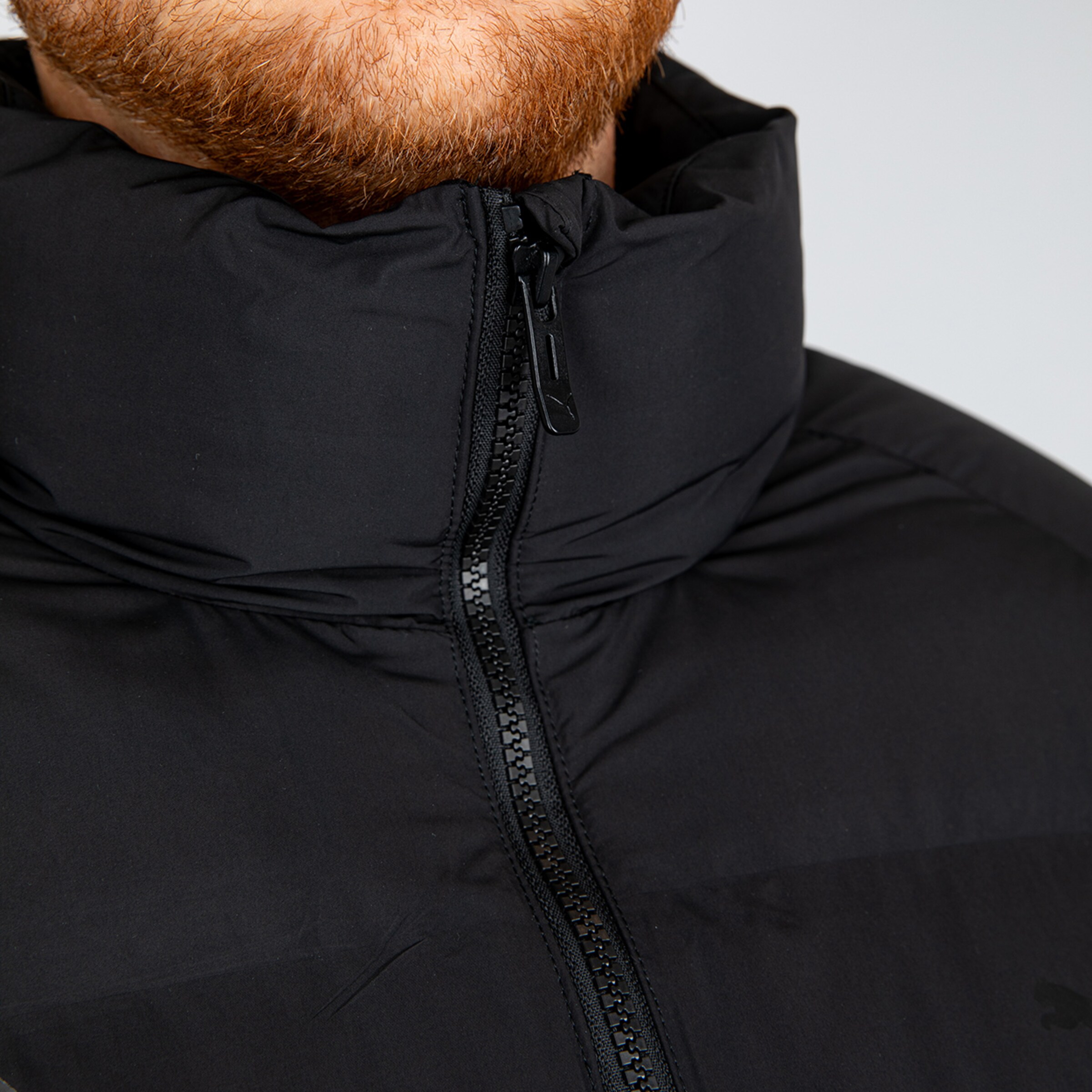 Nahaufnahme eines Mannes mit Bart in einer schwarzen Jacke.