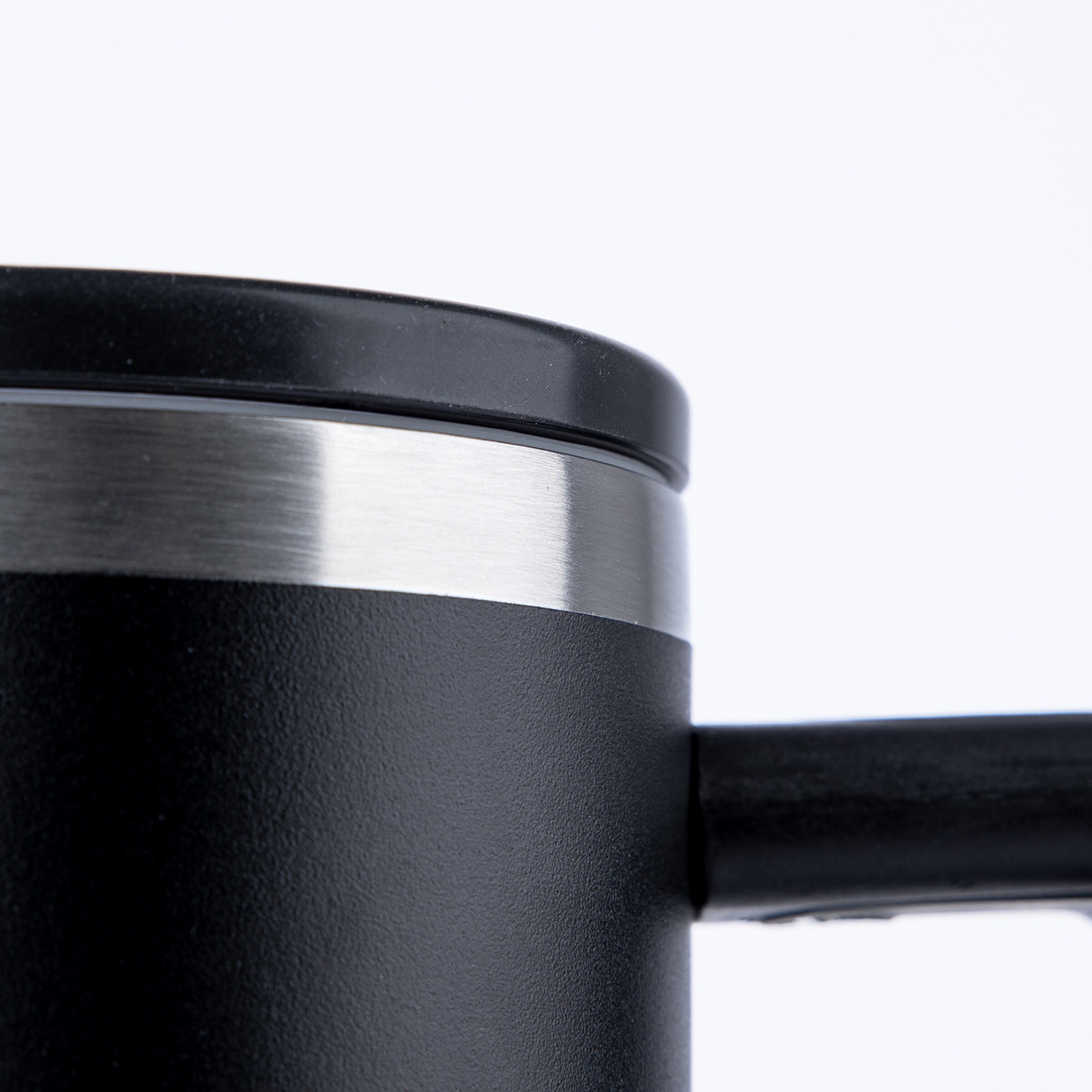 Nahaufnahme eines schwarzen Reisebechers mit silbernem Metallrand, schwarzem Deckel und Griff vor weißem Hintergrund.