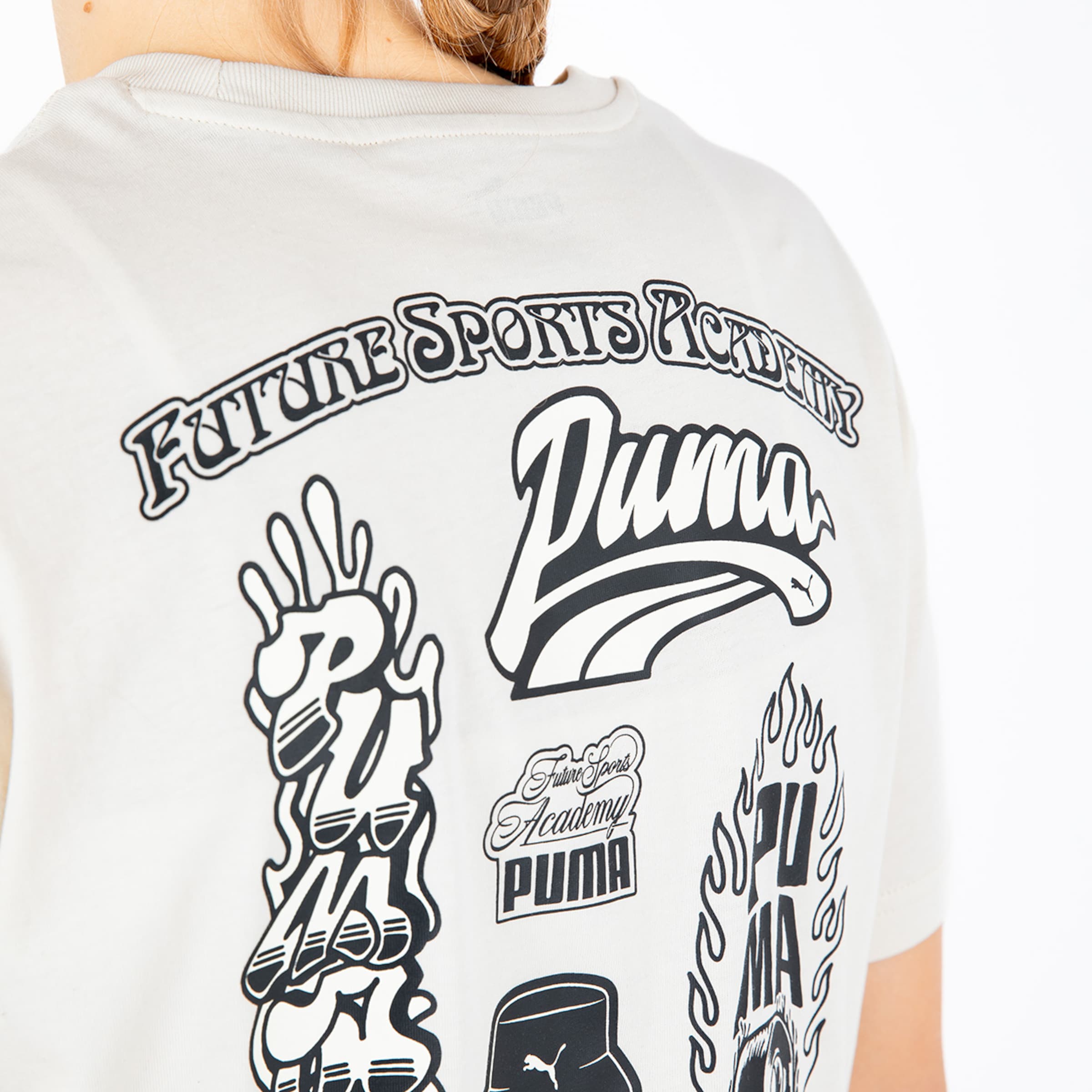 Rückansicht eines cremefarbenen T-Shirts mit verschiedenen schwarzen Puma-Grafikprints und dem Schriftzug „Future Sports Academy“.