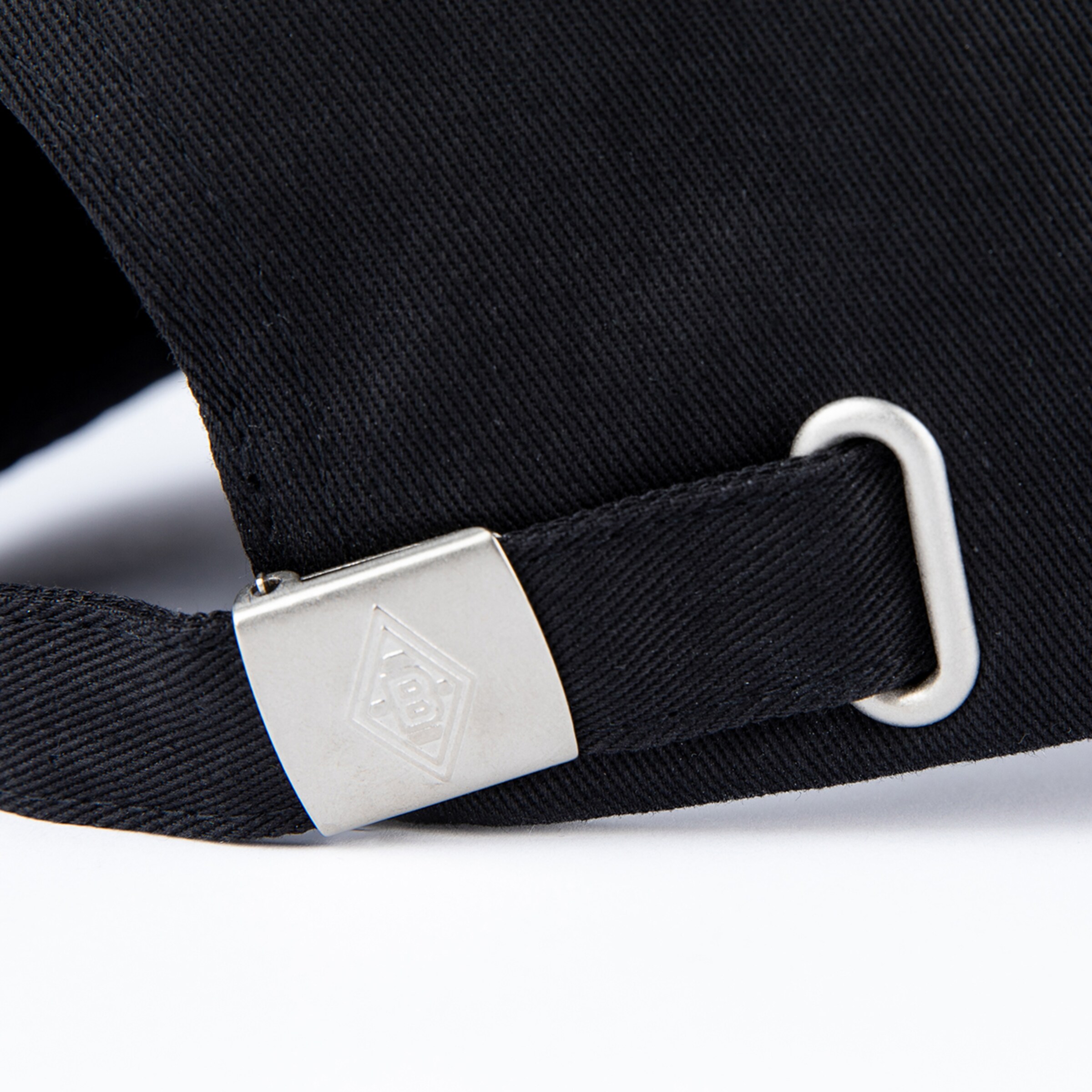 Einstellbarer Riemen einer schwarzen Mütze mit Metallverschluss.